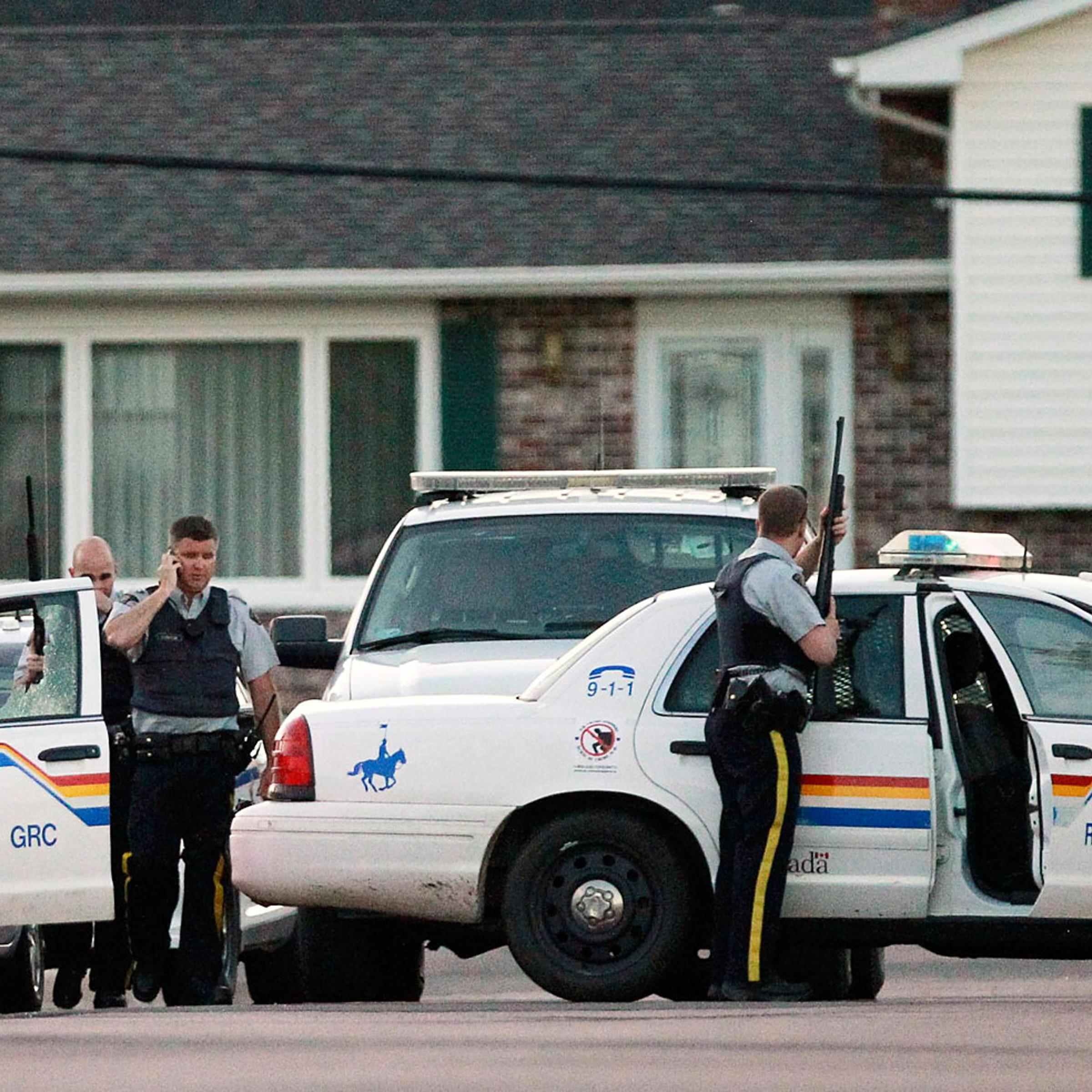 Codiac RCMP officers take cover behind their vehicle in Moncton