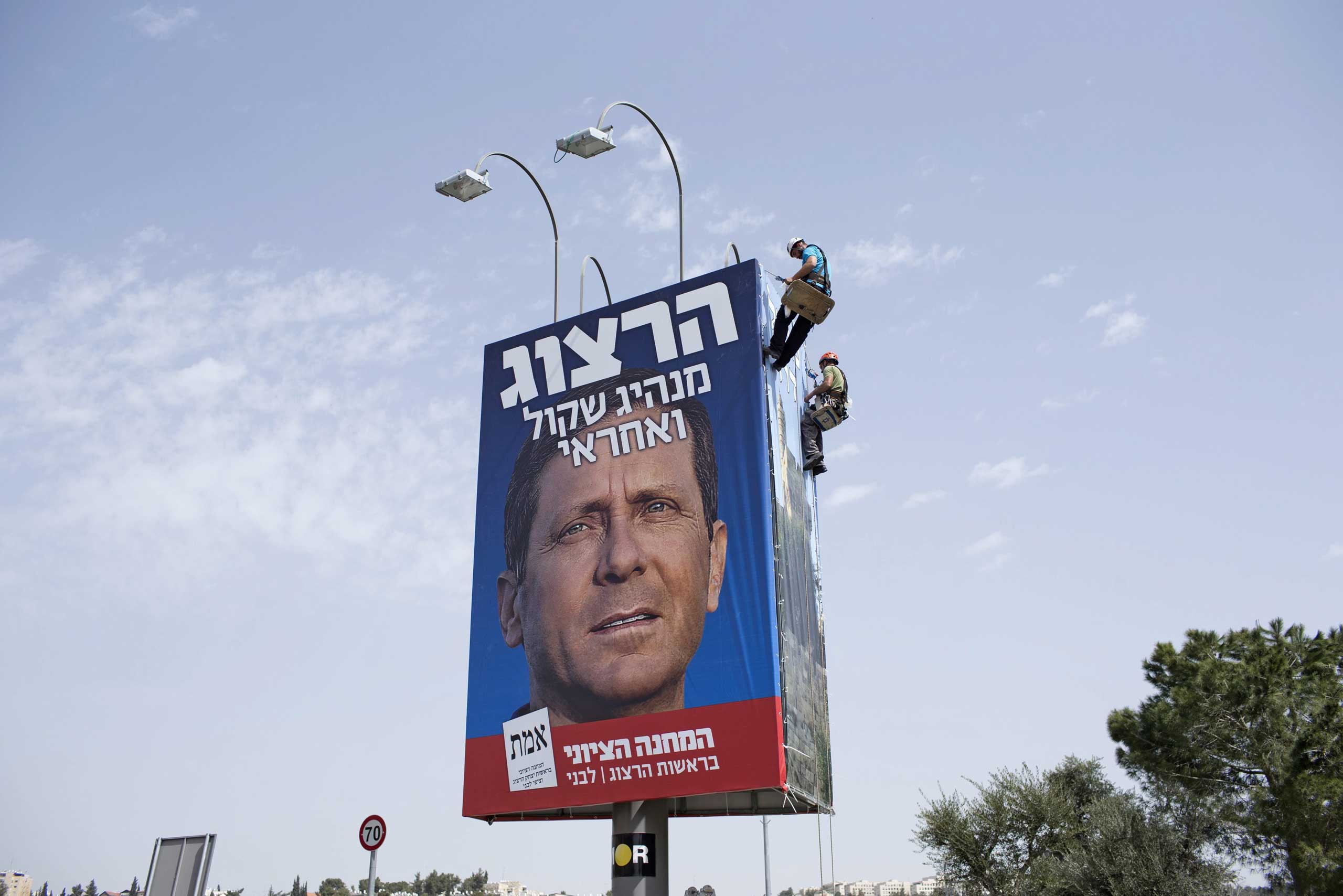 Workers erect a large billboard of co-leader of the Zionist Union, Isaac Herzog, on a highway in Jerusalem,11 March 2015.