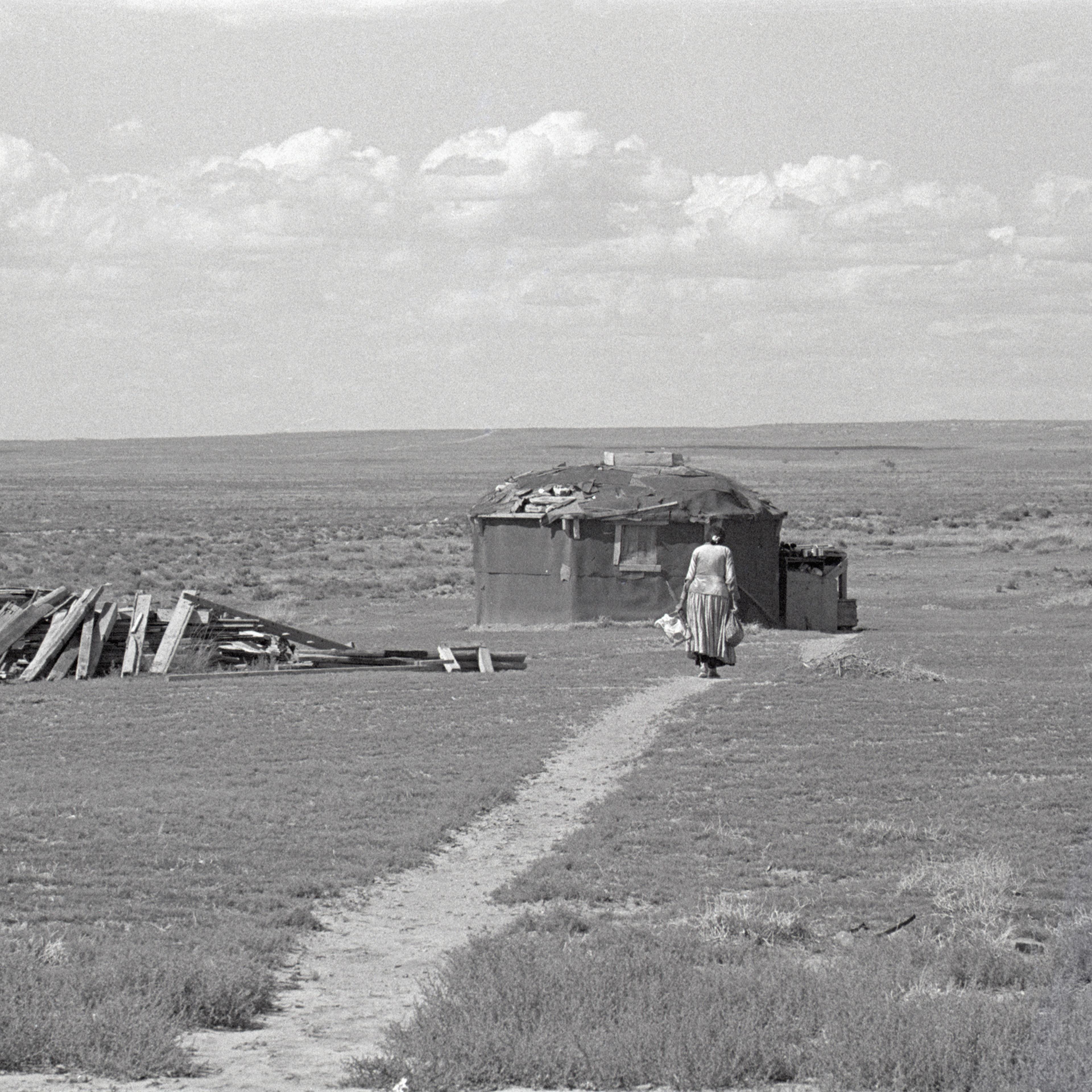 Navajo Woman Walking Towards Hogan