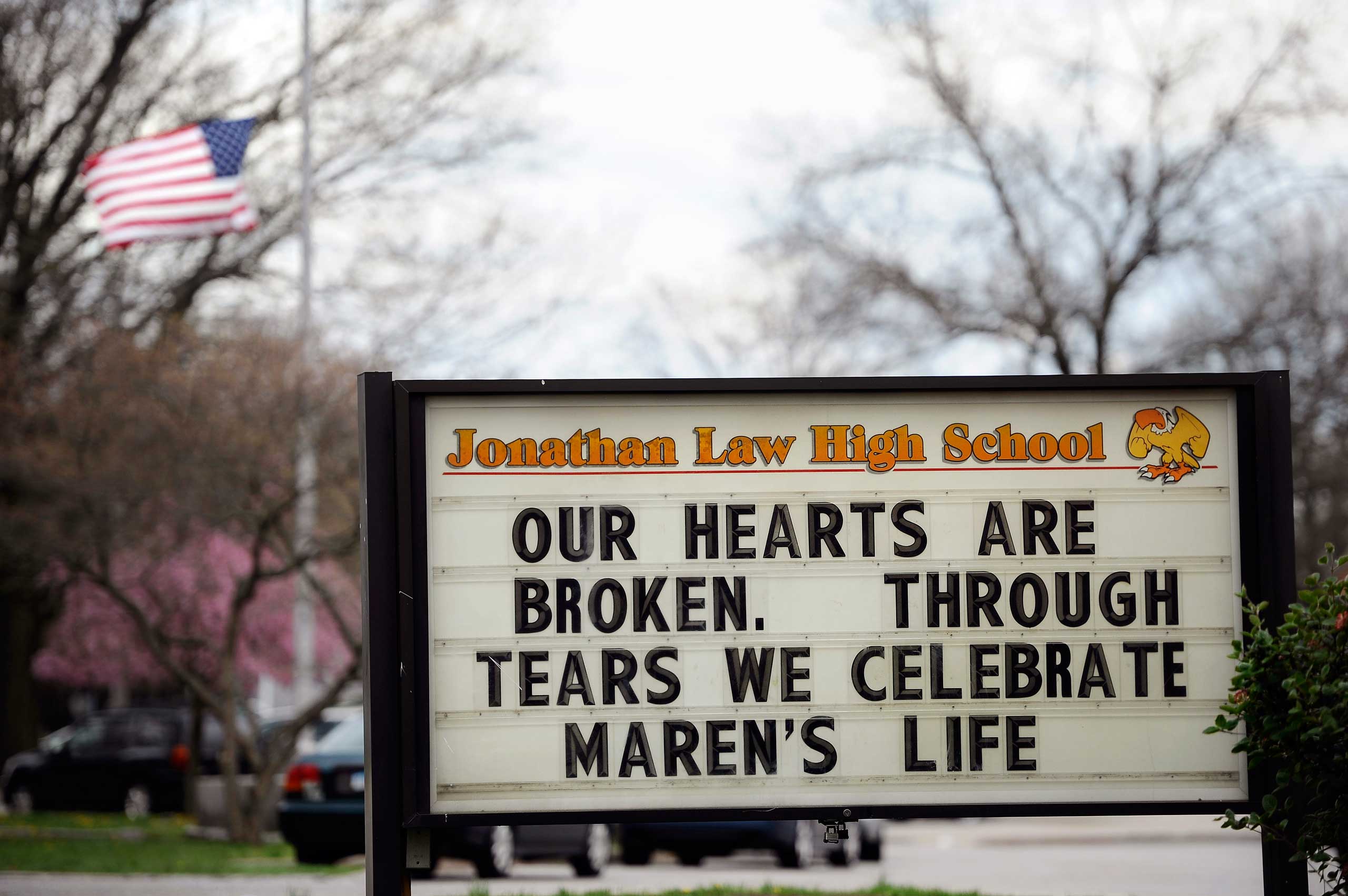 A sign at the entrance to Jonathan Law High School memorializes Maren Sanchez as a flag at half-staff blows in the distance on school grounds in Milford, Conn., on May 2, 2014.
