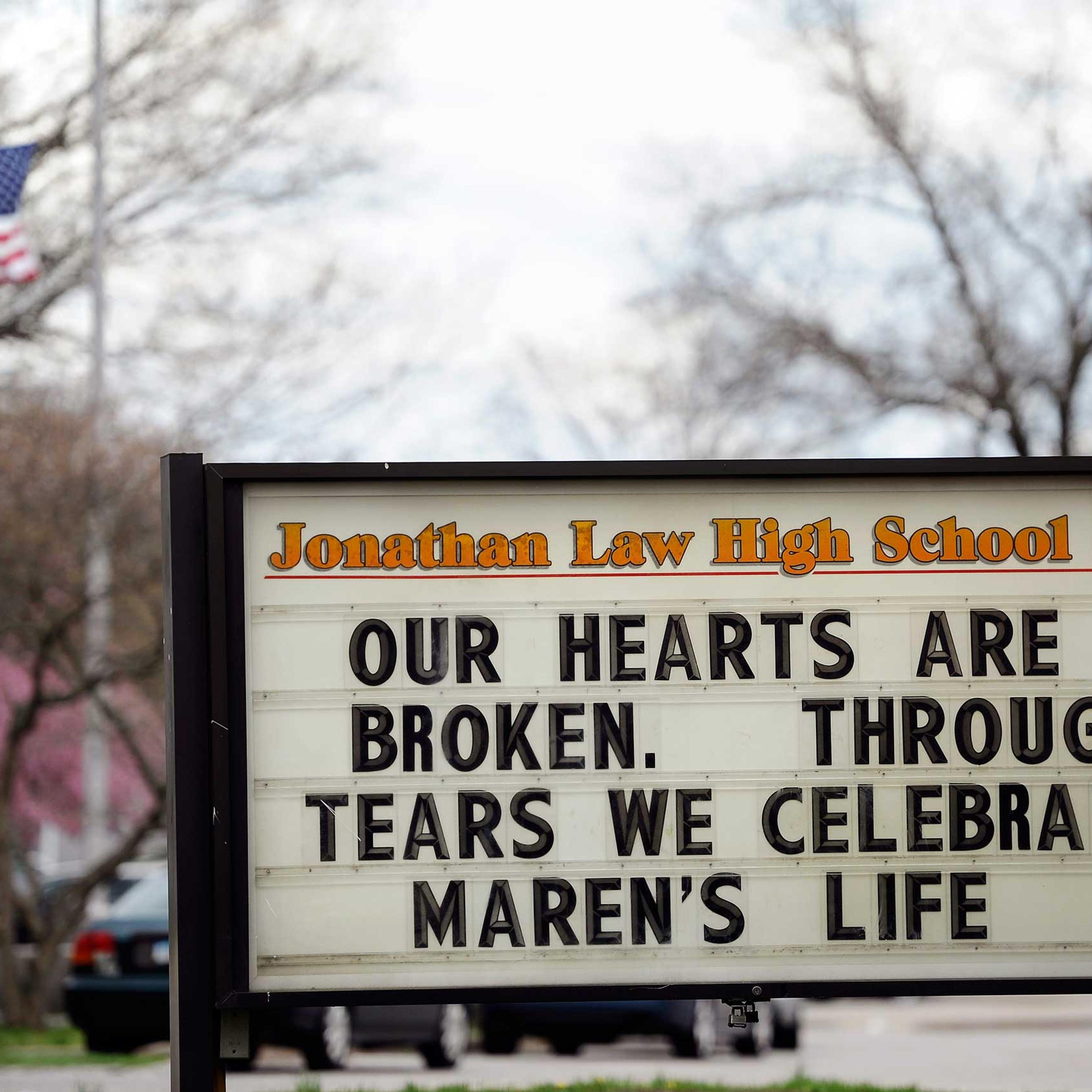 A sign at the entrance to Jonathan Law High School memorializes Maren Sanchez as a flag at half-staff blows in the distance on school grounds in Milford, Conn., on May 2, 2014.