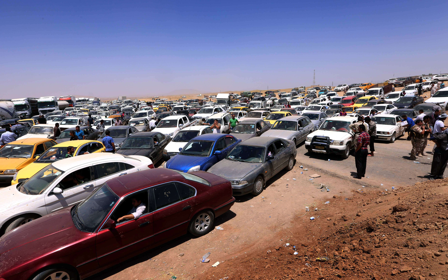 Iraqis fleeing violence in the Nineveh province wait in their vehicles at a Kurdish checkpoint in Aski Kalak, 25 miles West of Arbil, the capital of the autonomous Kurdish region of northern Iraq, on June 10, 2014.