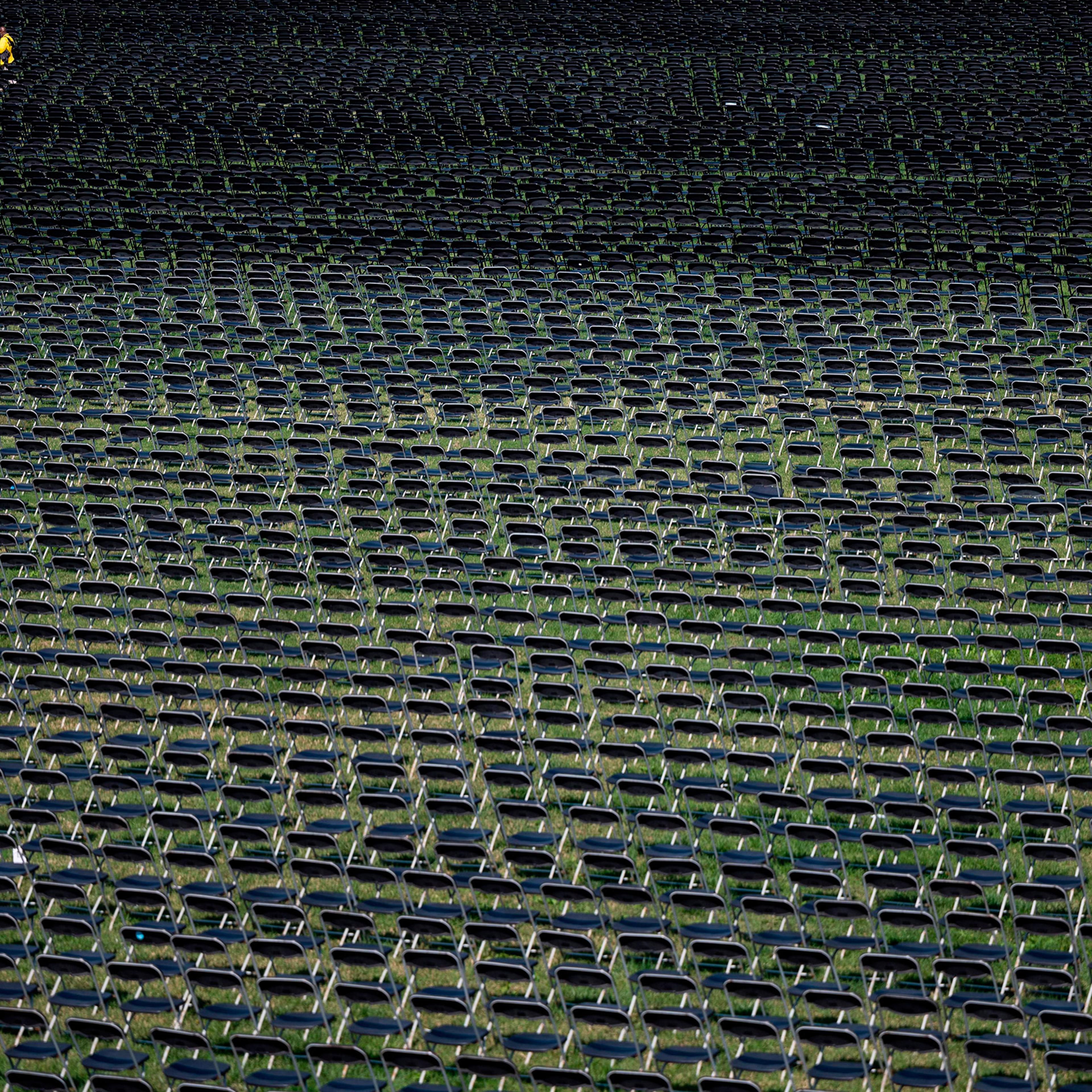 An event staff member walks past the empty chairs on display to represent the 200,000 lives lost due to COVID-19 on the ellipse behind the White House on Oct. 4