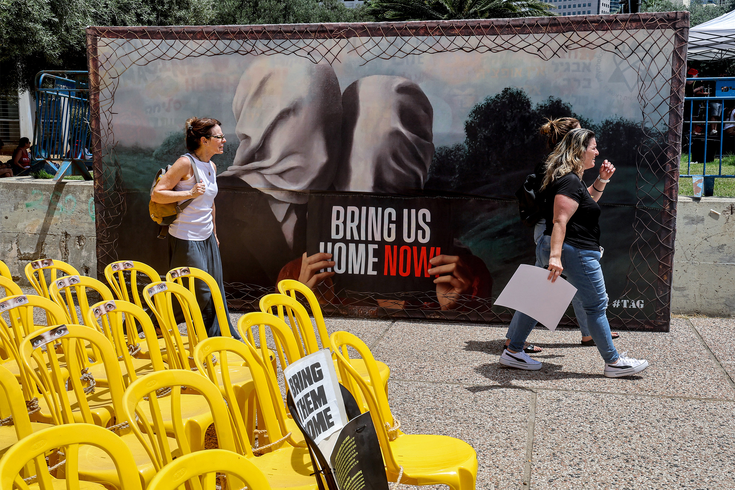 Women walk past an installation of empty chairs during a demonstration by the mothers and relatives of Israelis held hostage in Gaza since the October 7 attacks, calling for efforts to save the hostages, outside the Charles Bronfman Auditorium at HaBima 