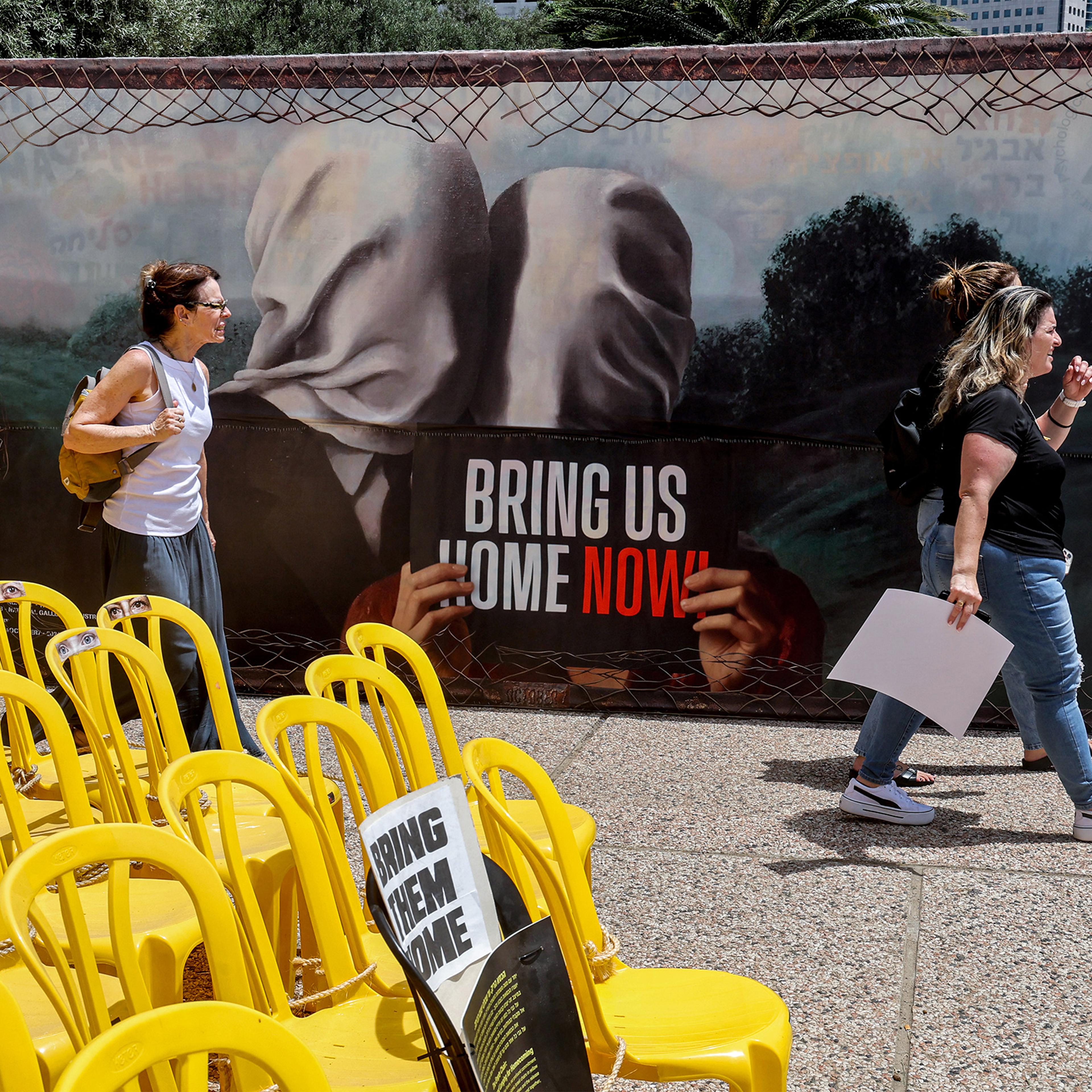 Women walk past an installation of empty chairs during a demonstration by the mothers and relatives of Israelis held hostage in Gaza since the October 7 attacks, calling for efforts to save the hostages, outside the Charles Bronfman Auditorium at HaBima