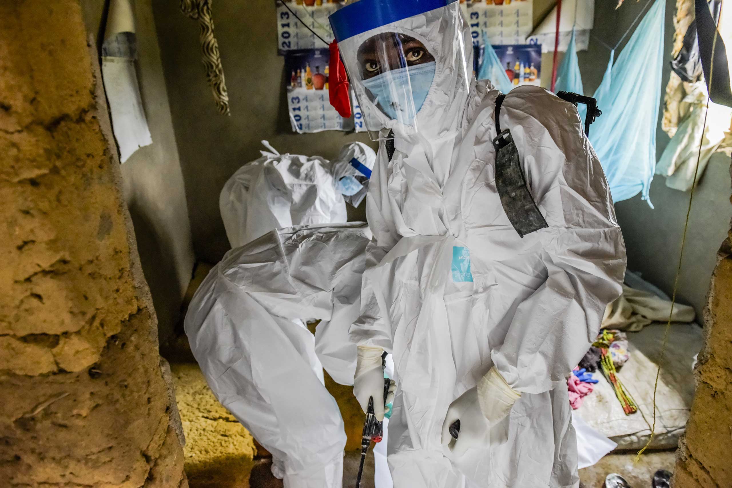 A burial team extracts the body of Isatu Sesay, 16, an Ebola victim, from her home in Kissi Town, Sierra Leone.