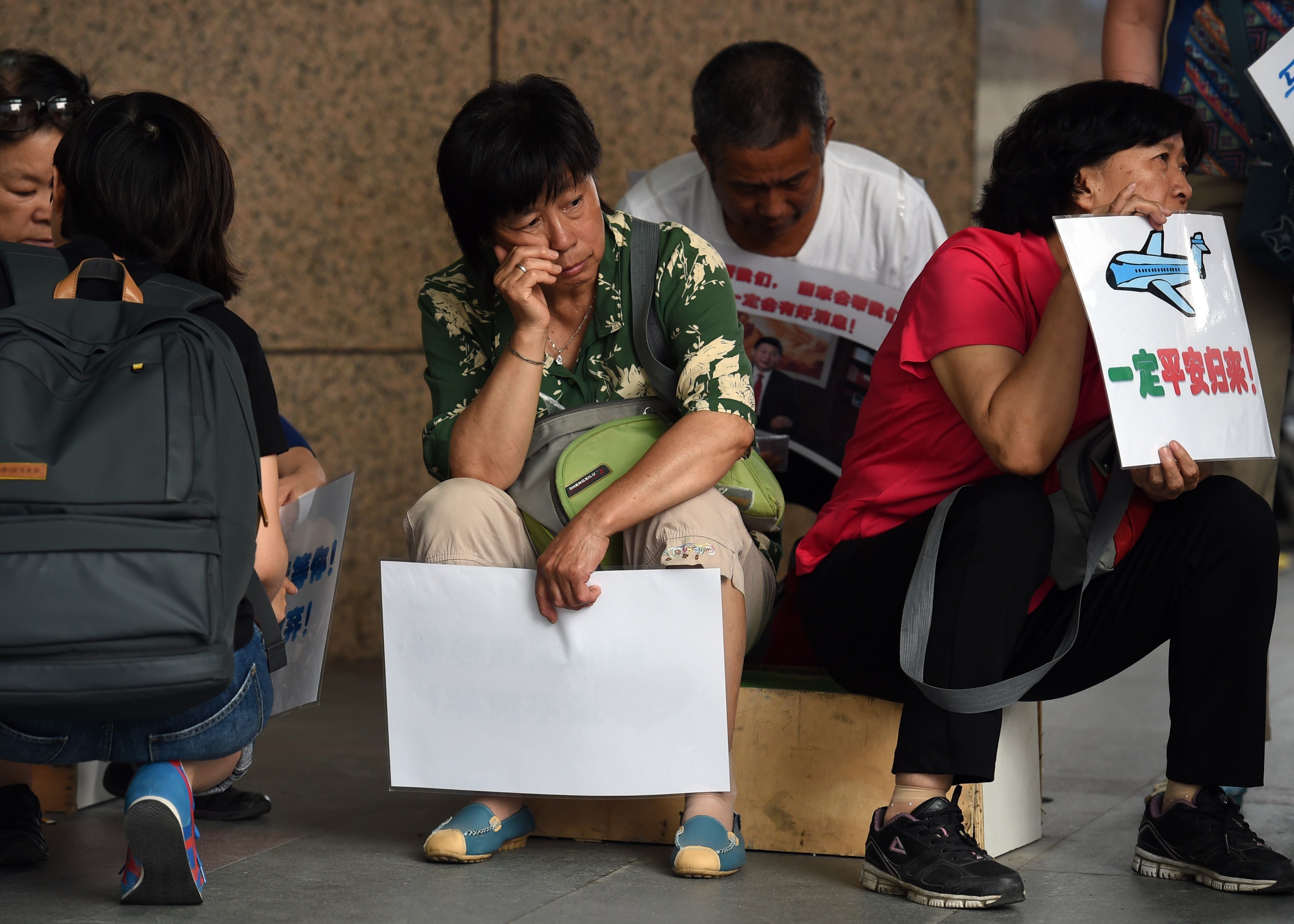 Relatives of passengers on missing Malaysia Airlines MH370 wait outside the Malaysia Airlines office in Beijing on Aug. 6, 2015.