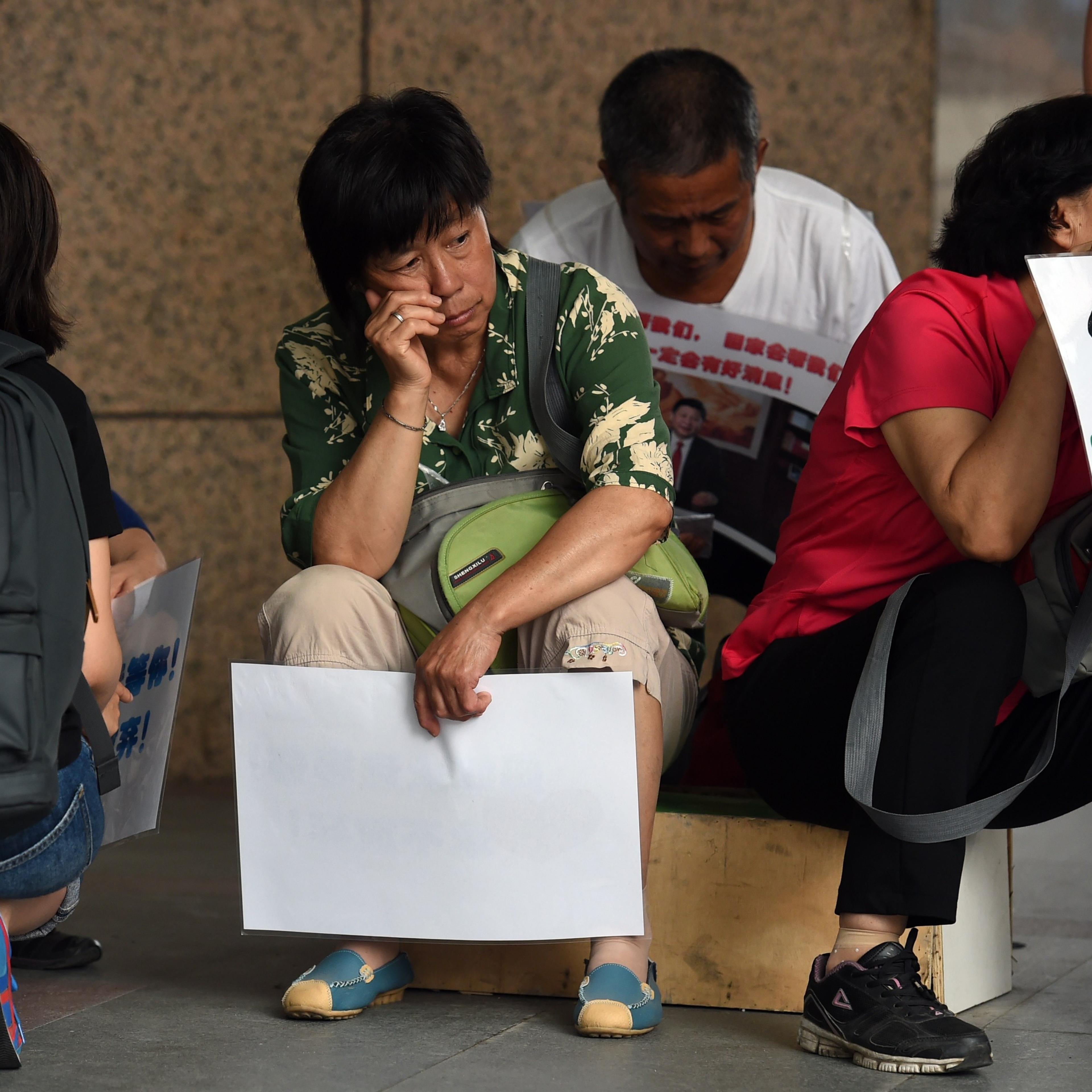 Relatives of passengers on missing Malaysia Airlines MH370 wait outside the Malaysia Airlines office in Beijing on Aug. 6, 2015.