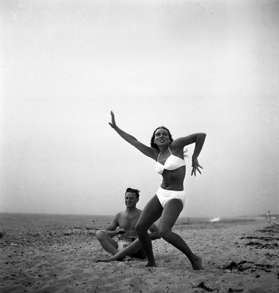 Caption from LIFE: "Ann Converse, member of old Boston family who works as Cape Cod waitress, expresses Activationist joy while friend beats oilcan tom-tom."