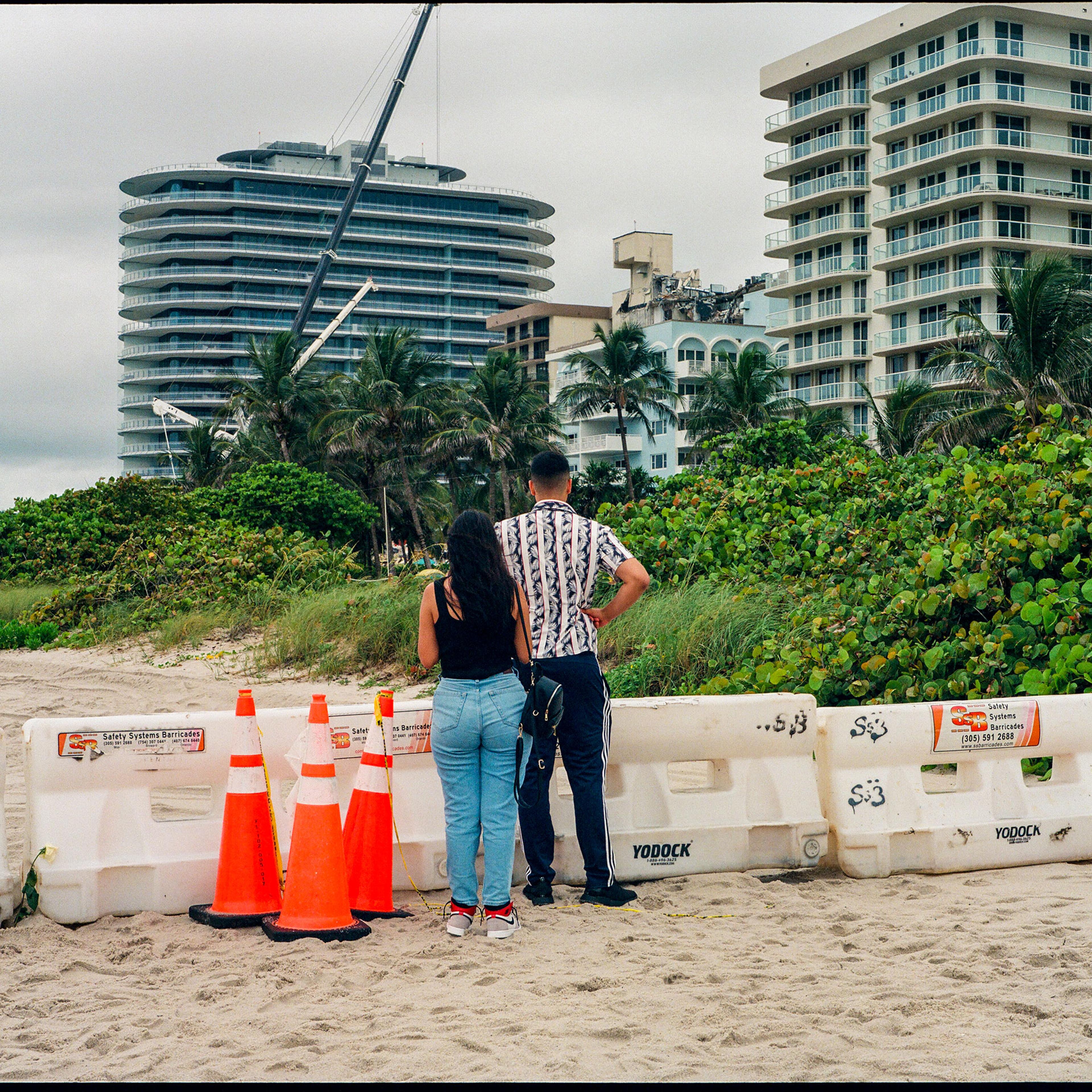 People look at the collapsed Champlain Towers South building from afar on Miami Beach in Surfside, Fla. on June 30, 2021.