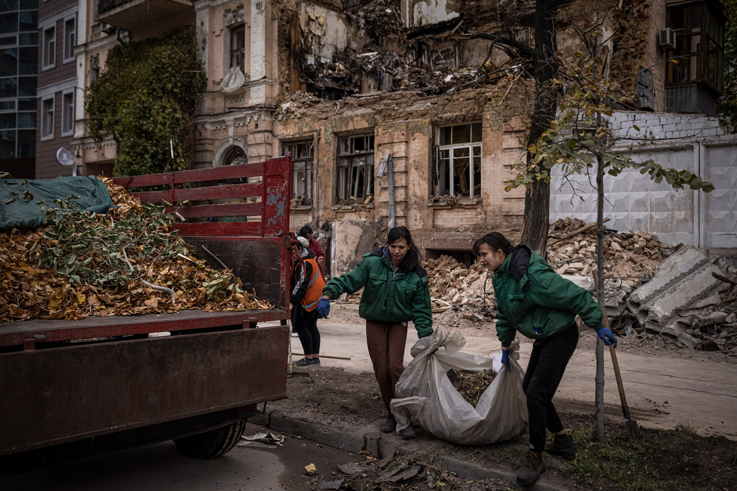 People clear blast debris and leaves outside a house where a couple was killed in a Russian drone strike two days beforehand on Oct.19 in Kyiv, Ukraine. 