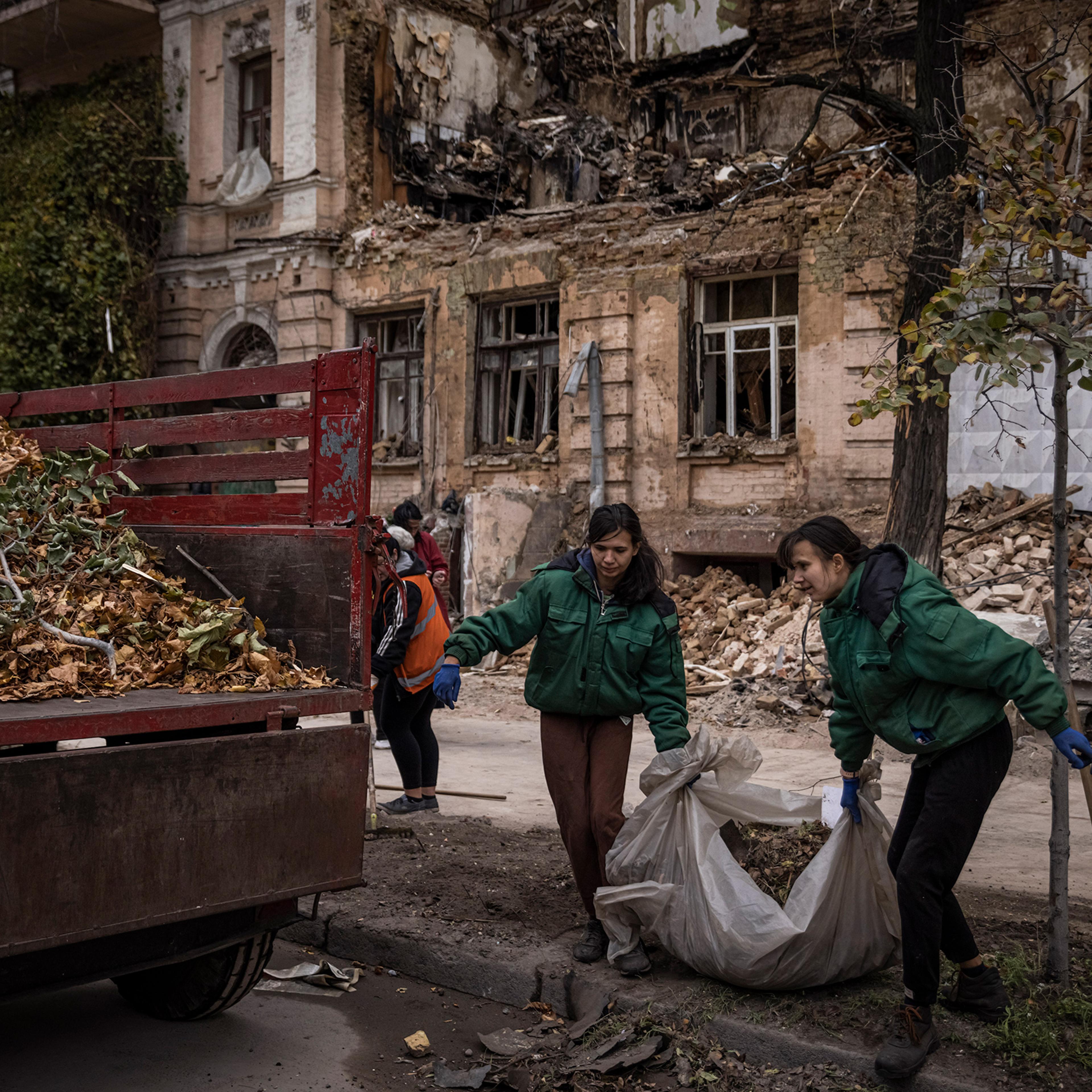 People clear blast debris and leaves outside a house where a couple was killed in a Russian drone strike two days beforehand on Oct.19 in Kyiv, Ukraine.