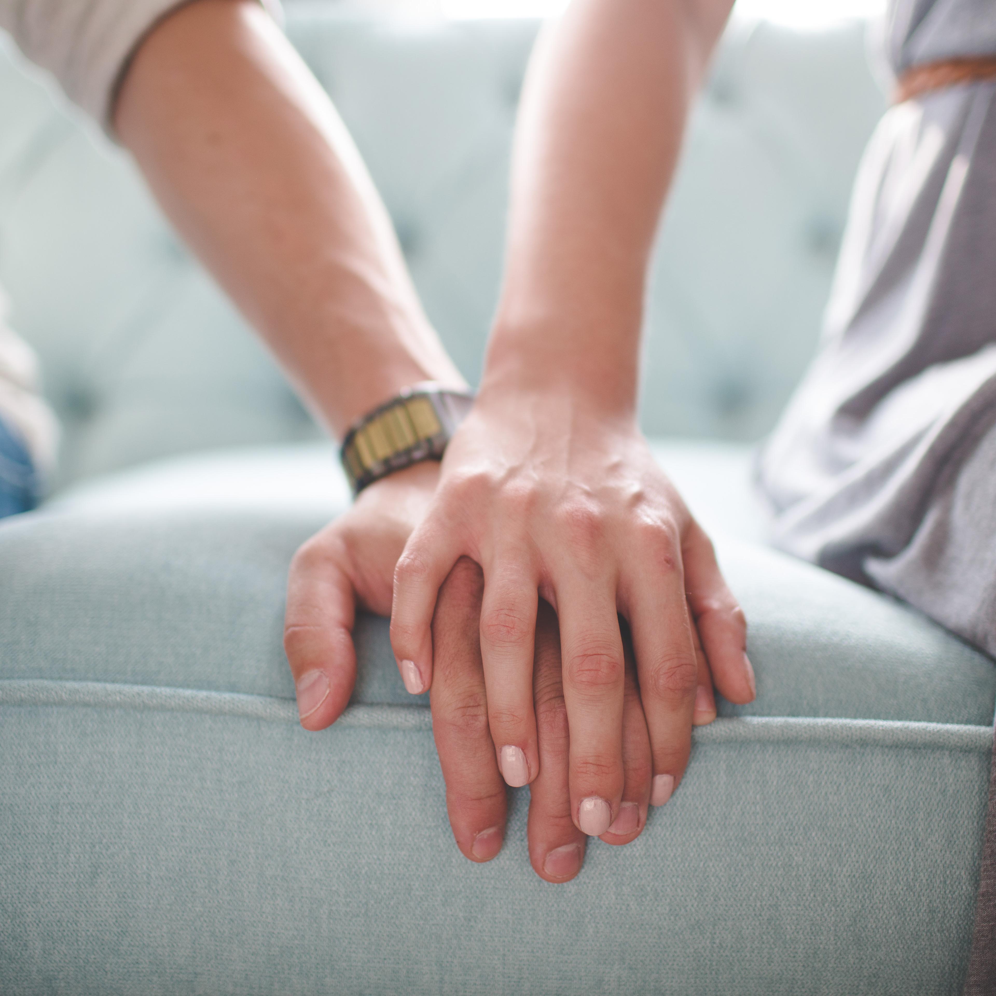Couple holding hands on sofa