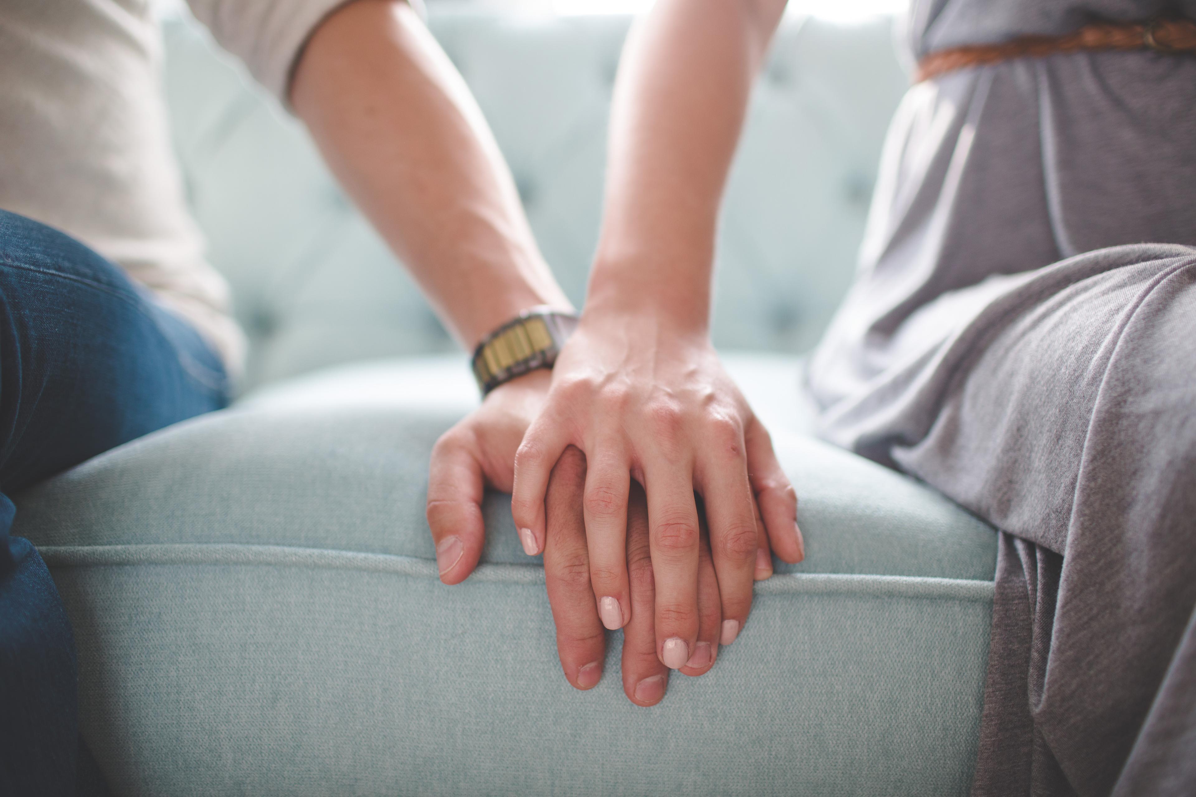 Couple holding hands on sofa