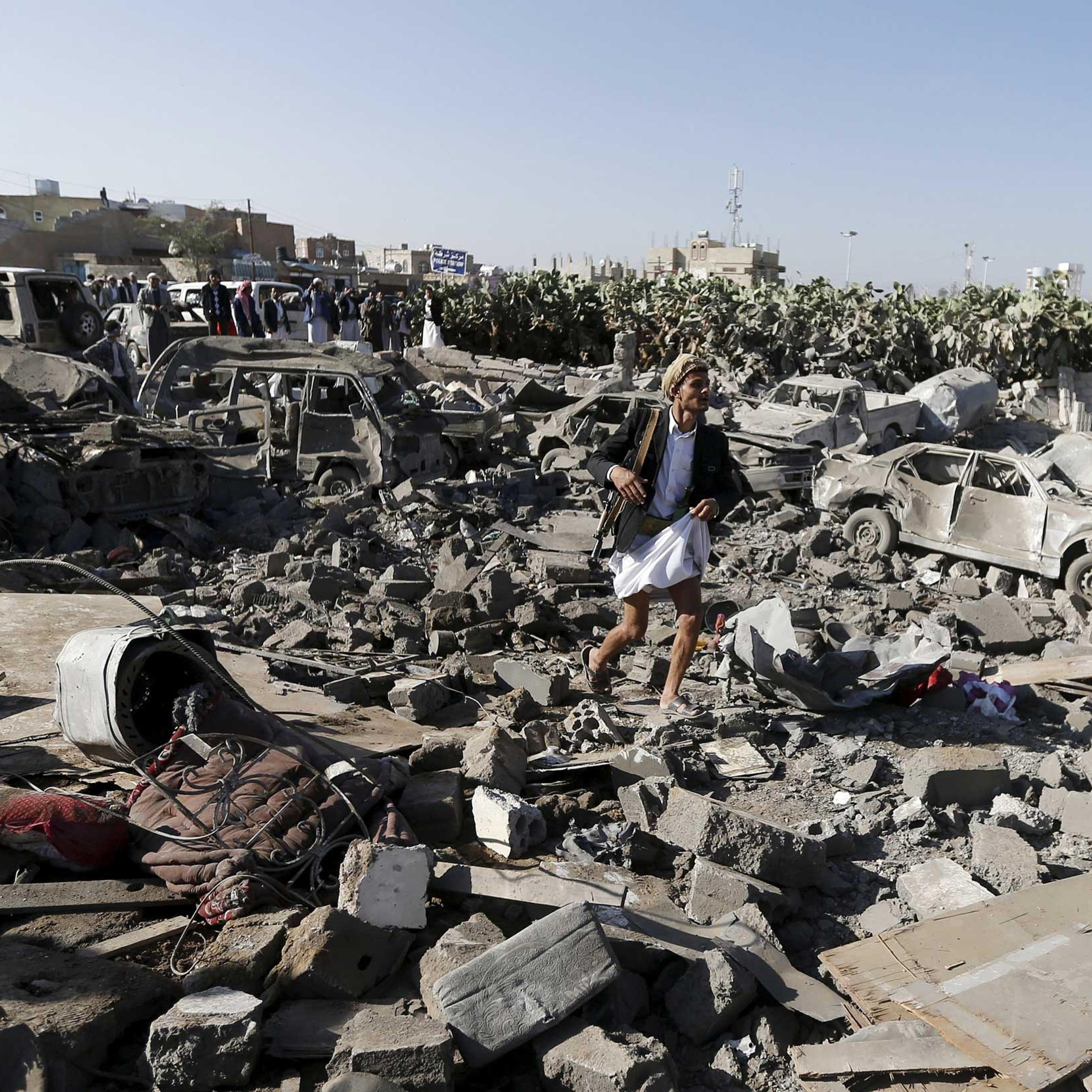 An armed man walks on the rubble of houses destroyed by an air strike near Sanaa Airport March 26, 2015.