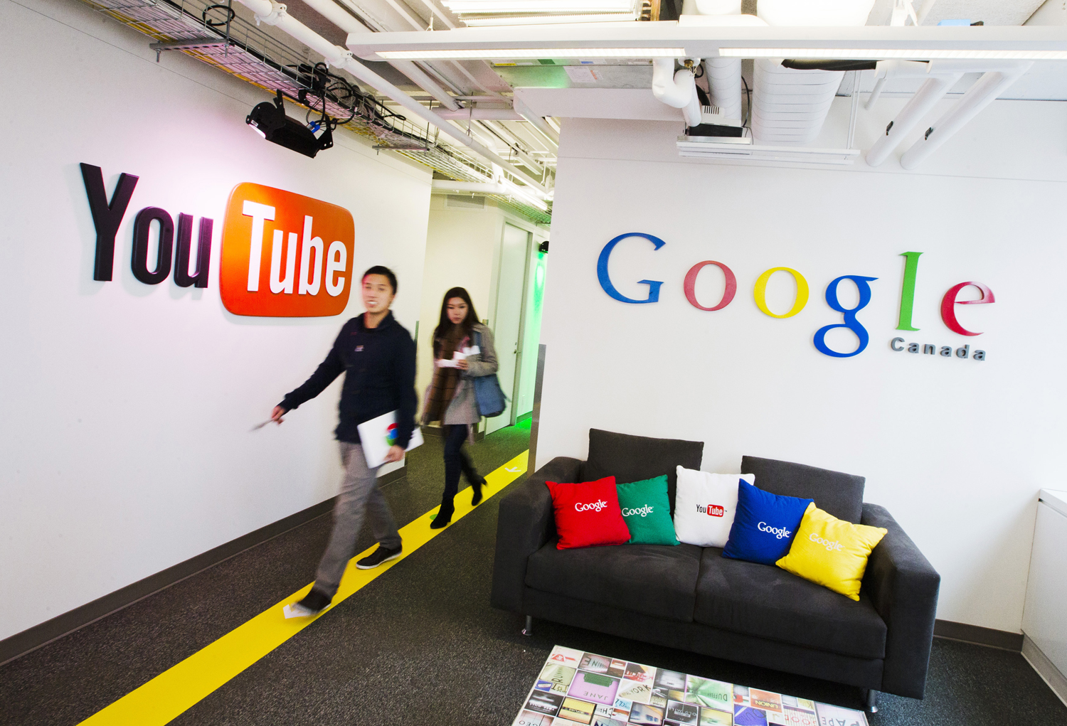 People walk by a YouTube sign at the new Google office in Toronto, Nov. 13, 2012.