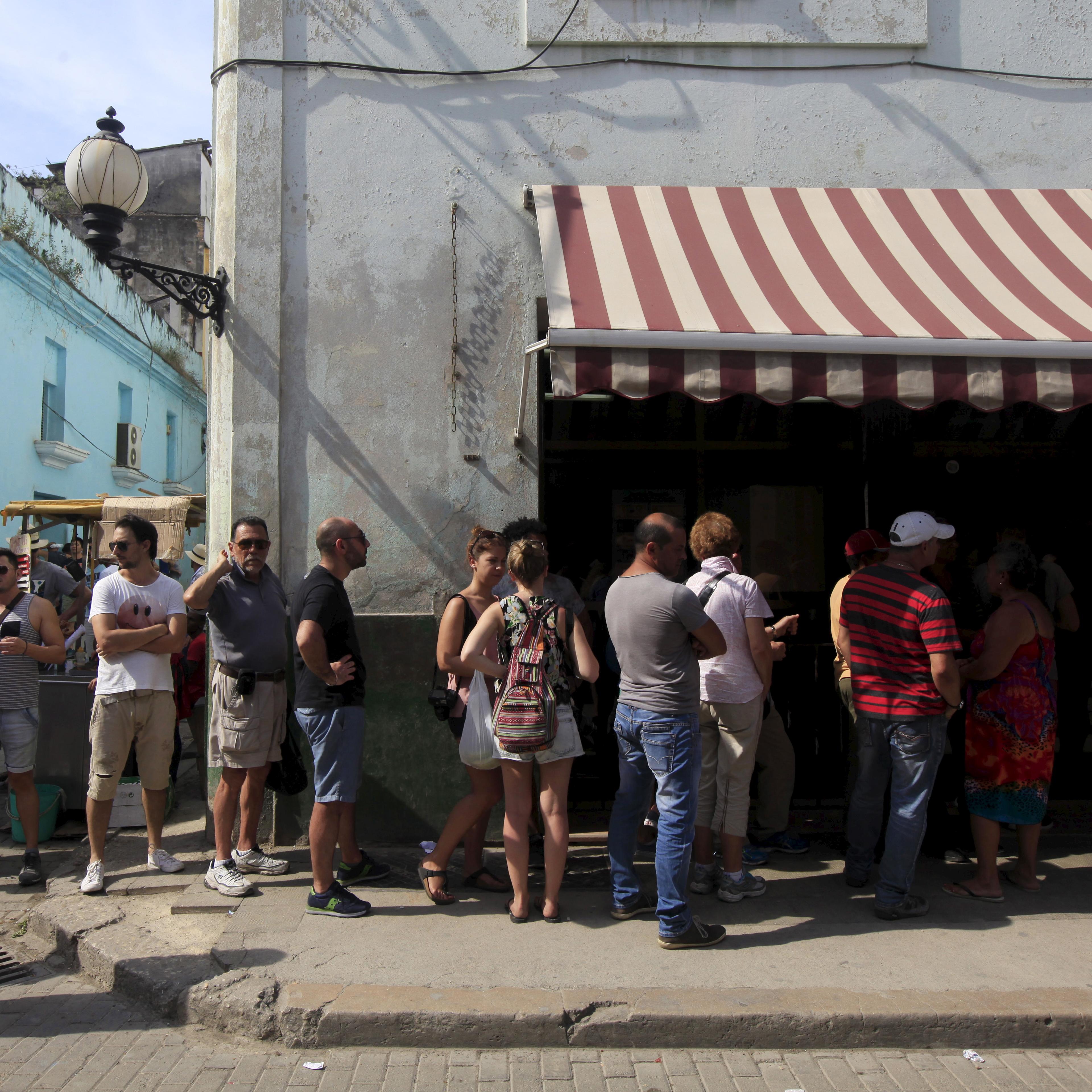 People stand outside a currency exchange shop to change money in Havana