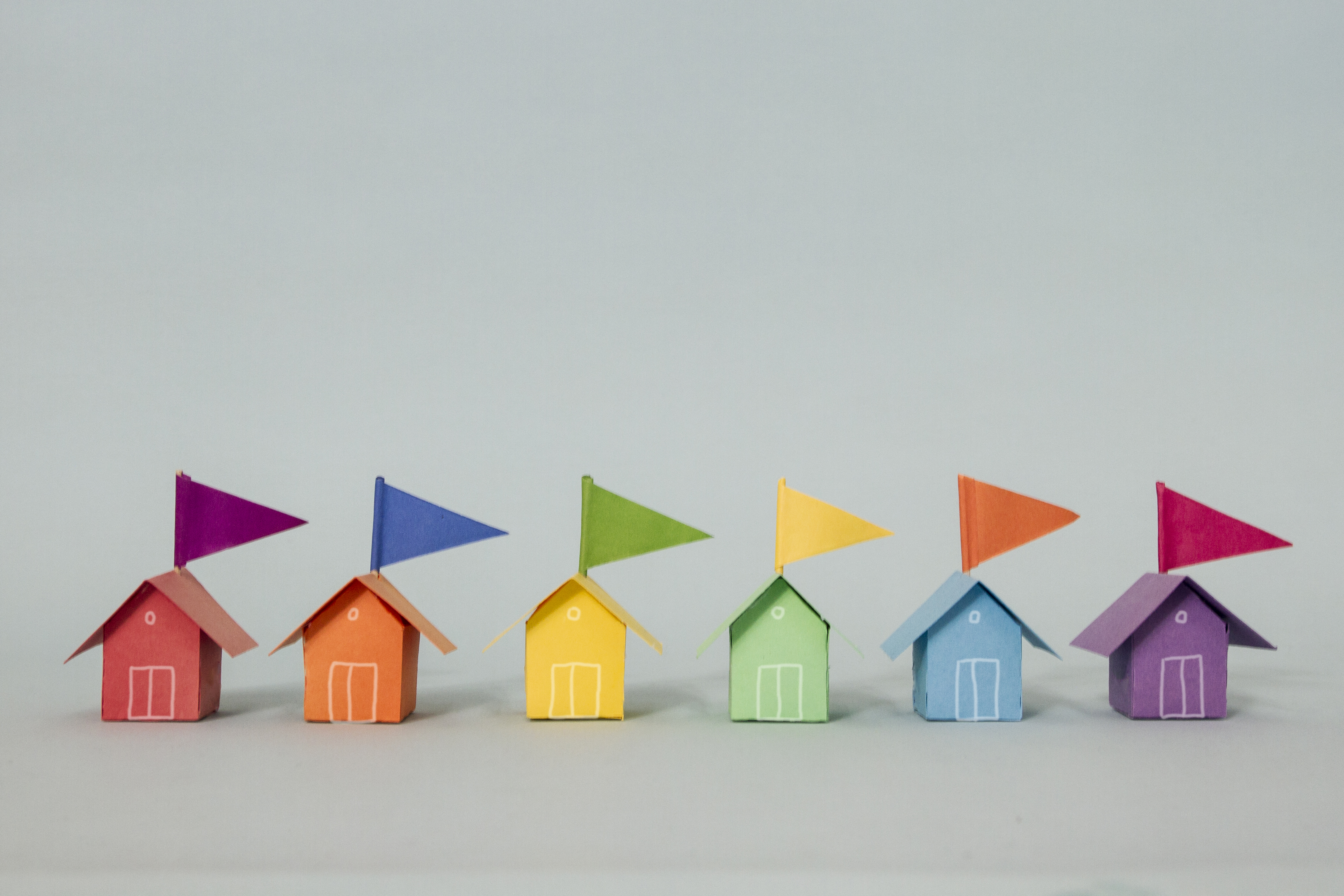 A row of rainbow coloured beach huts complete with contrasting paper flags made out of paper
