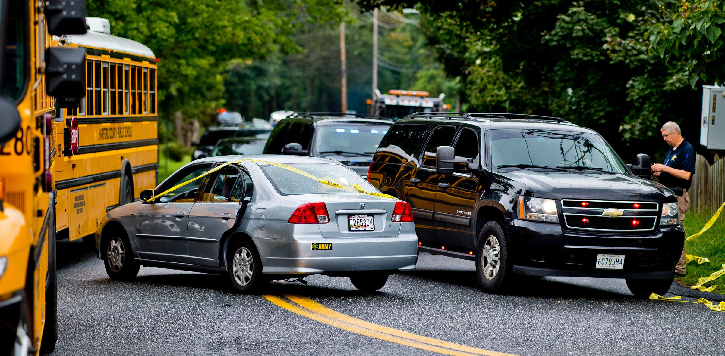 A victim's car (C) covered in crime scene tape as police search for a gunman who fled the scene of a shooting at a Rite Aid Distribution Center in Aberdeen, Maryland, on Sept. 20, 2018. The school busses (L) were brought to the scene to transport witness
