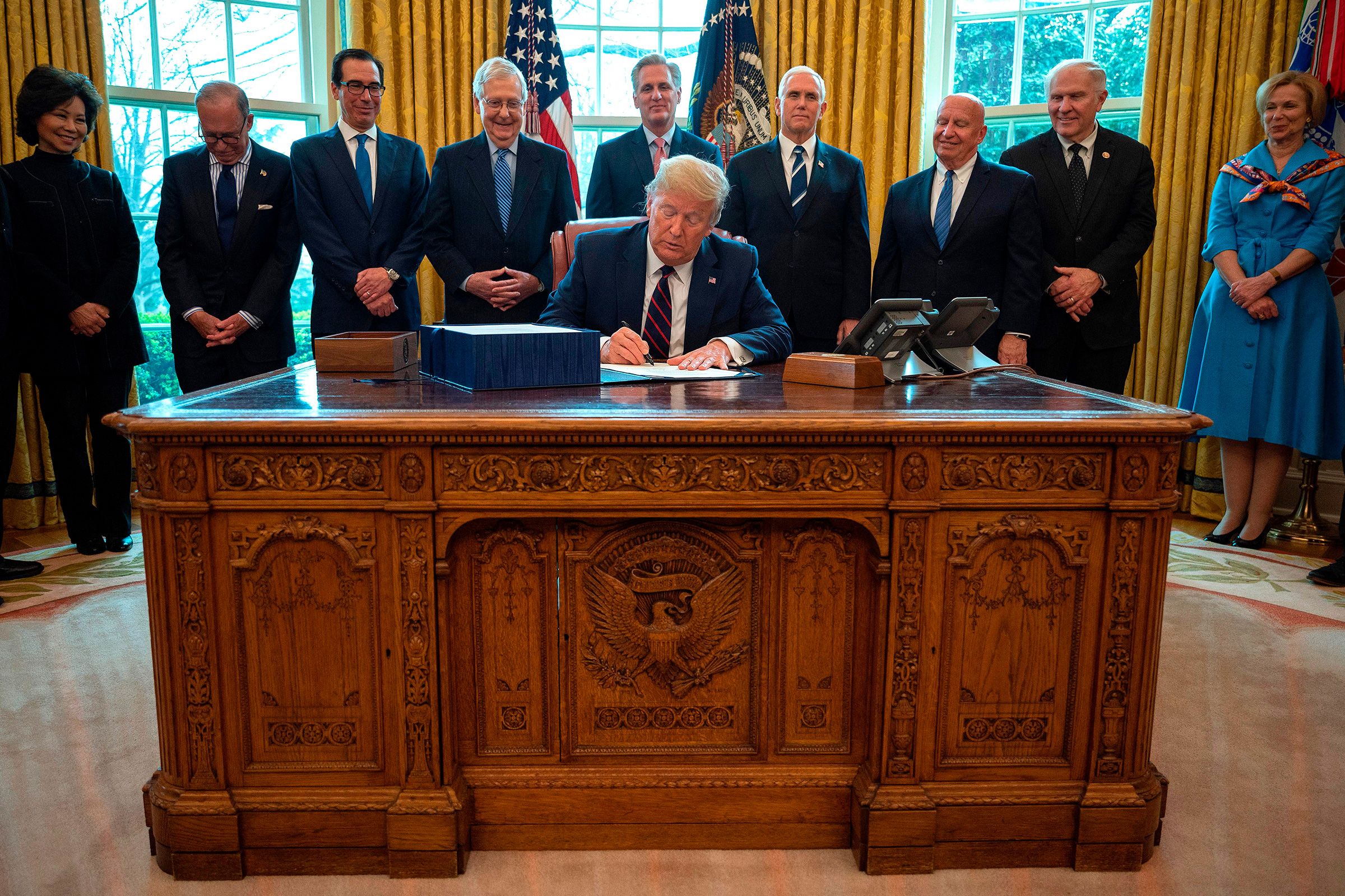President Donald Trump signs the CARES act, a $2 trillion rescue package to provide economic relief amid the coronavirus outbreak, at the Oval Office of the White House on March 27