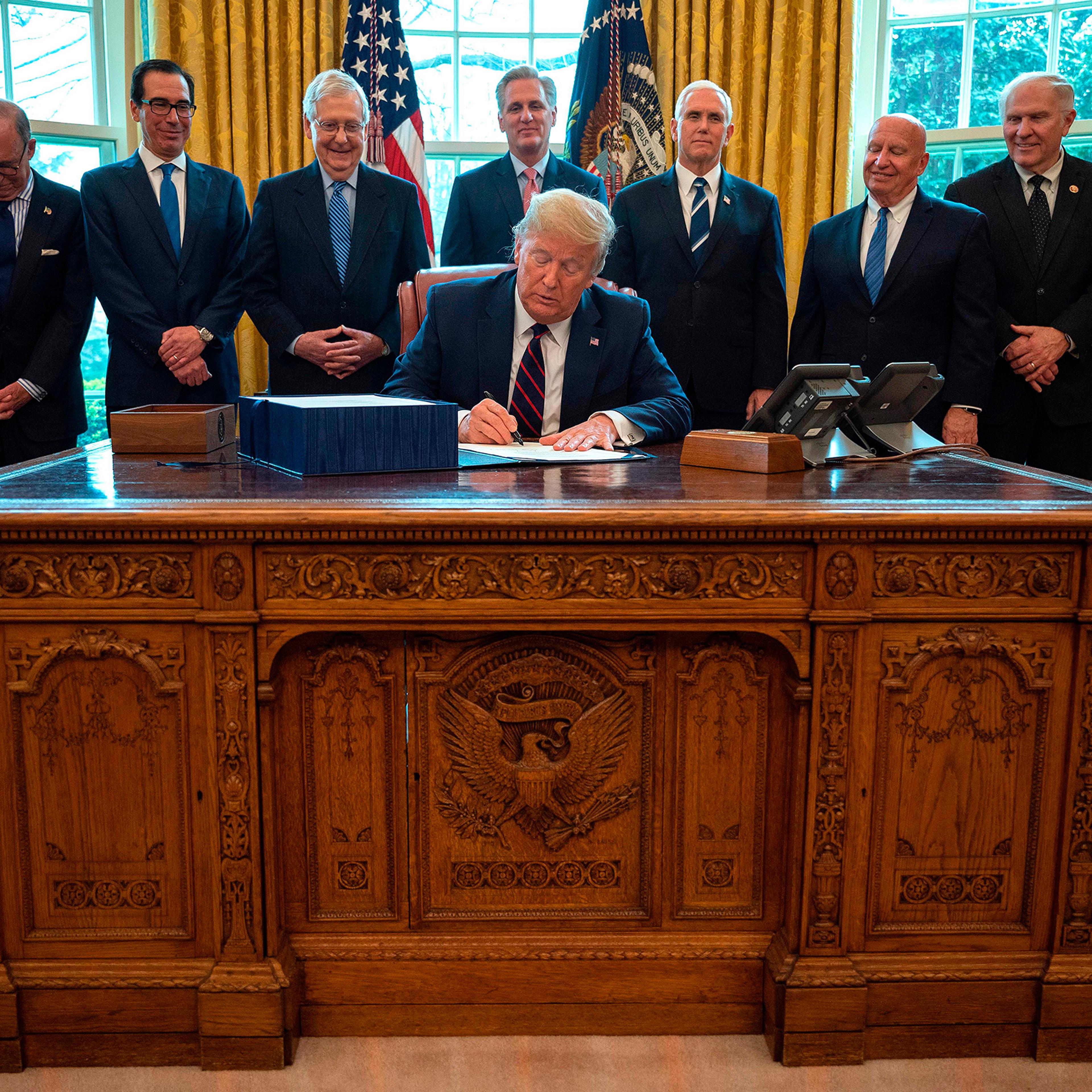 President Donald Trump signs the CARES act, a $2 trillion rescue package to provide economic relief amid the coronavirus outbreak, at the Oval Office of the White House on March 27