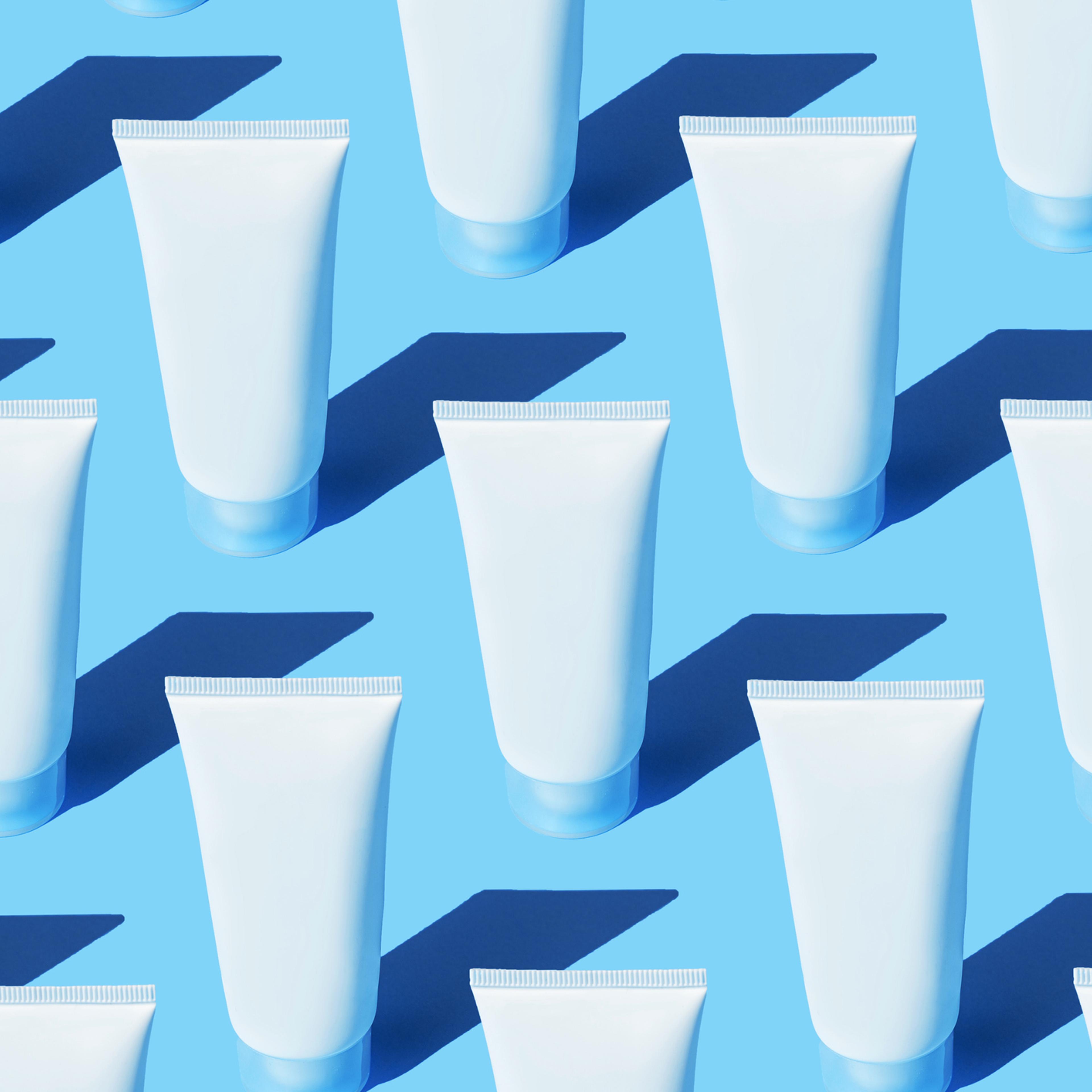 Skin care Pattern made of the tubes with Beauty Product Facial Cream or Hand Cream, Milk Cleansing Foam, Lotion, Shampoo on pastel turquoise blue color background.