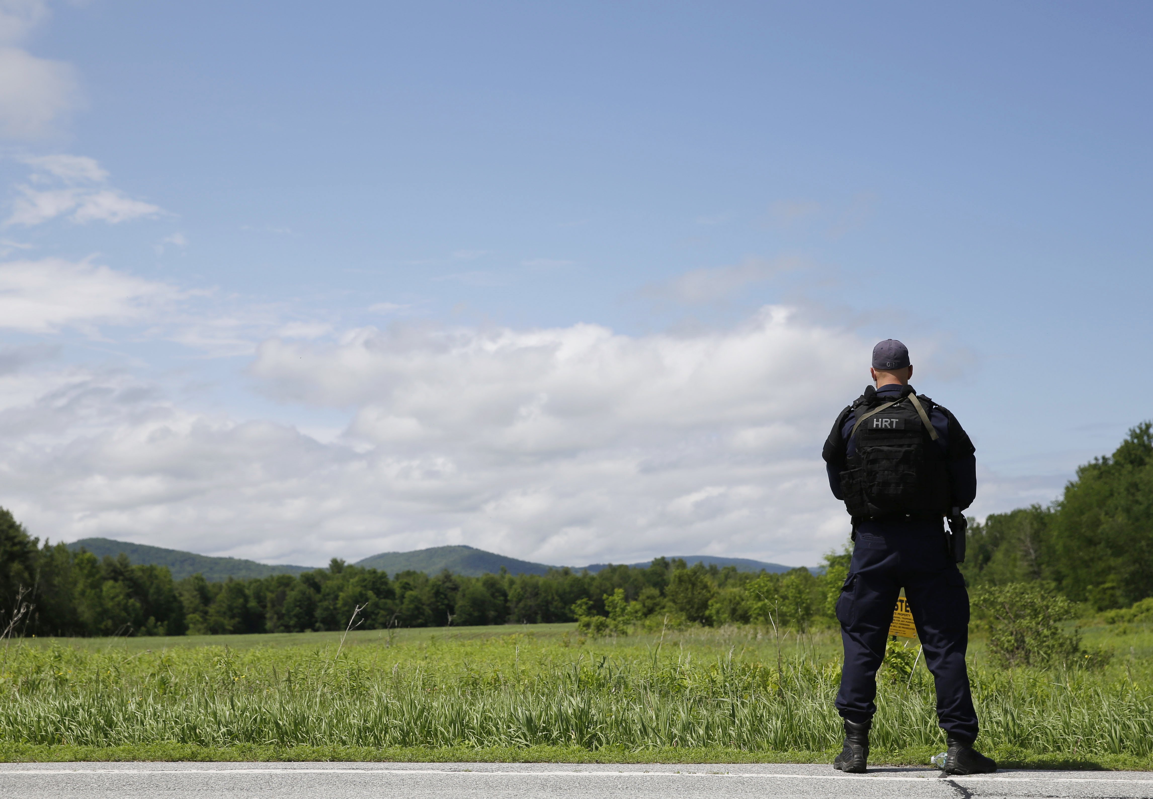 A heavily armed law enforcement officer patrols the edge of road during a search for two escaped killers in Boquet, N.Y. on June 9, 2015.