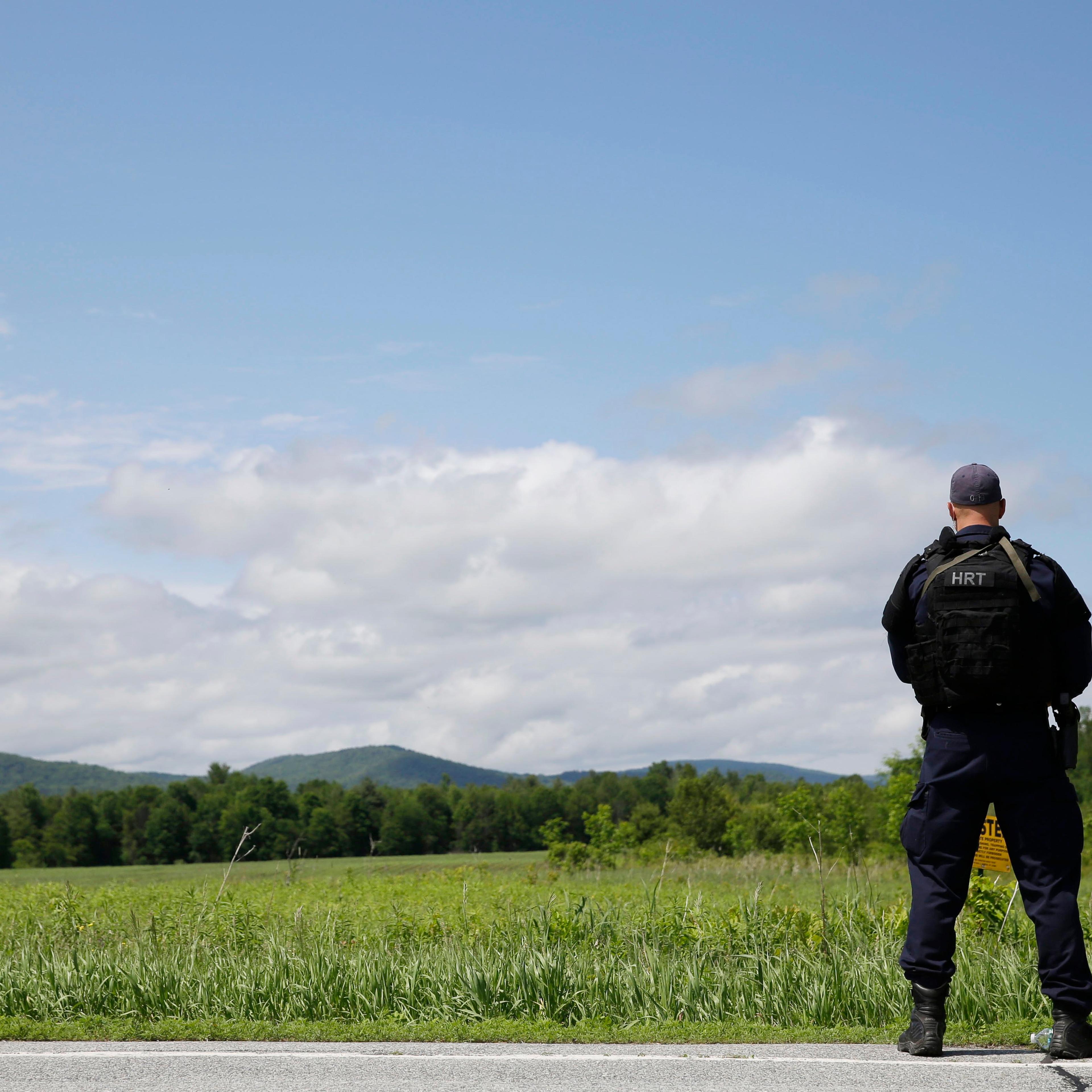 A heavily armed law enforcement officer patrols the edge of road during a search for two escaped killers in Boquet, N.Y. on June 9, 2015.