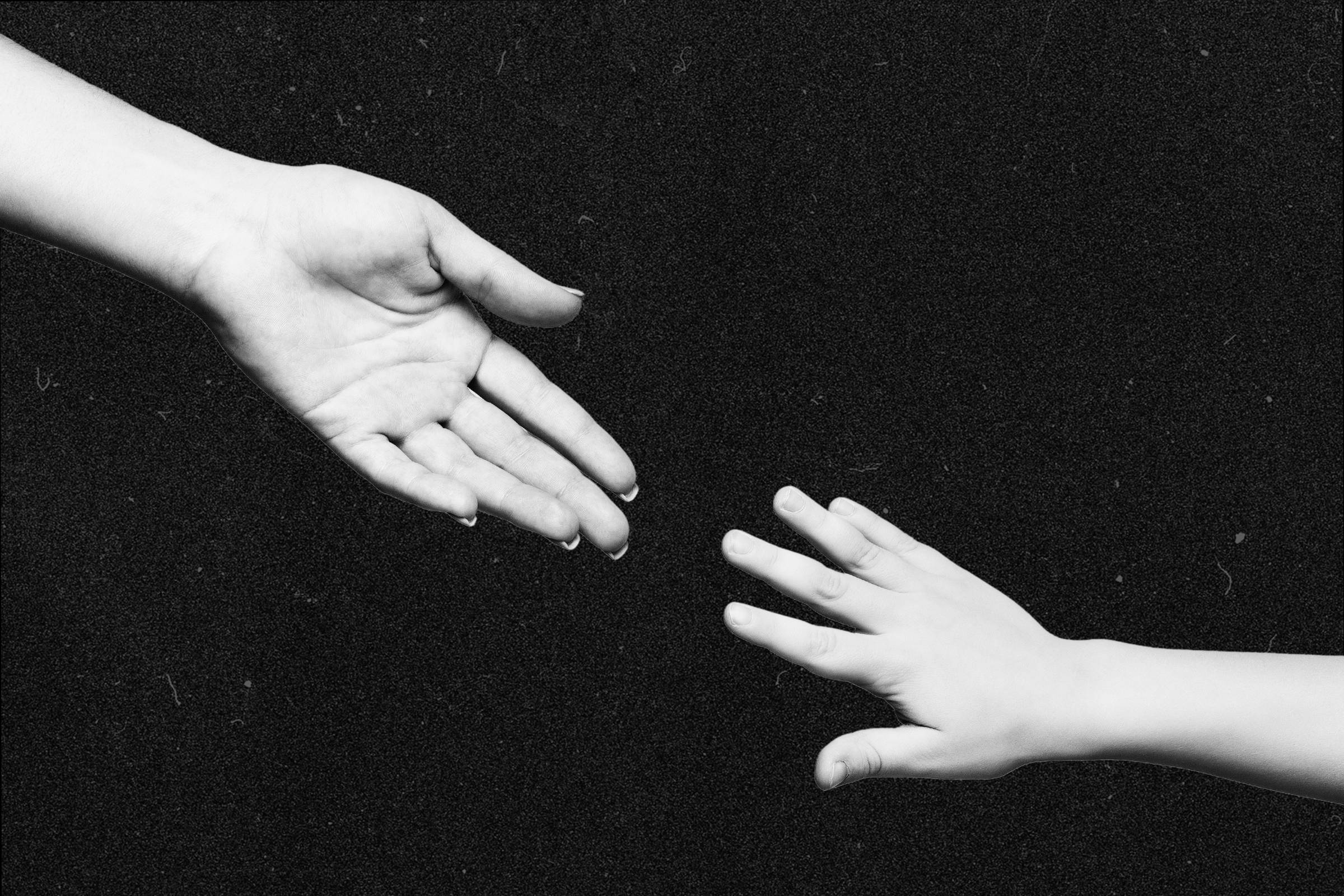 An adult hand reaching for a childs hand