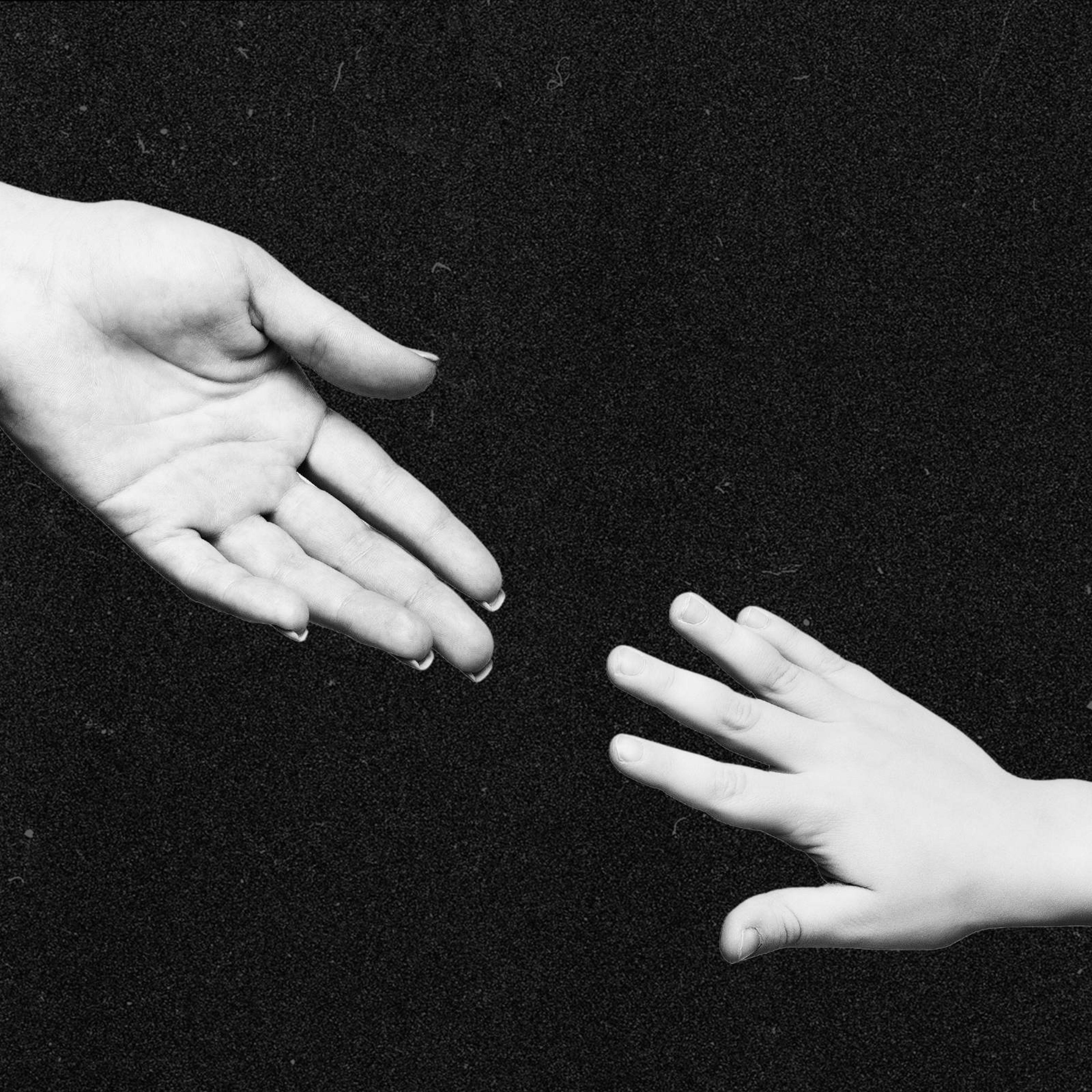 An adult hand reaching for a childs hand