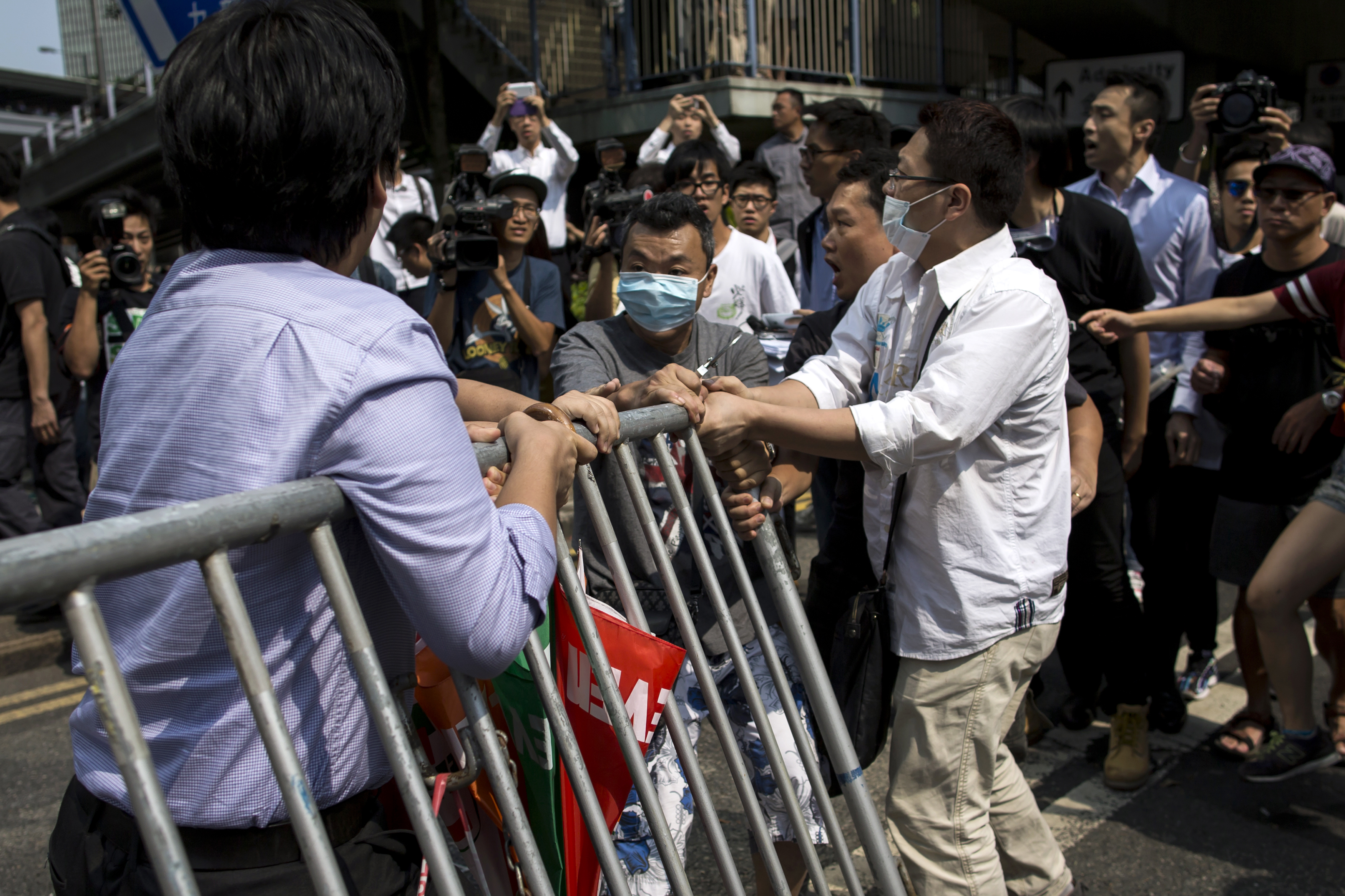 Masked anti-Occupy Central protesters try to remove barricades set up as road blocks by pro-democracy protesters in the Central financial district in Hong Kong