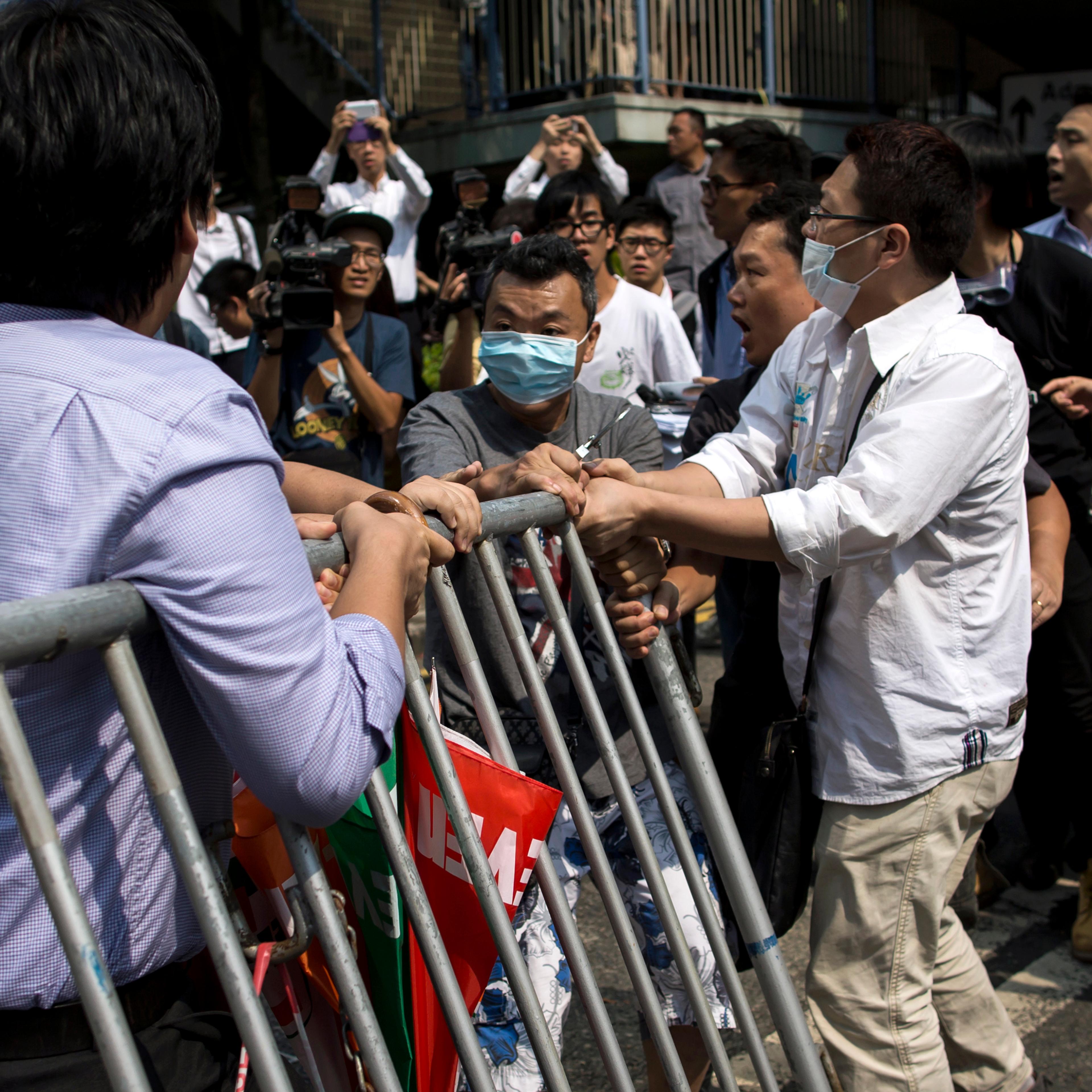 Masked anti-Occupy Central protesters try to remove barricades set up as road blocks by pro-democracy protesters in the Central financial district in Hong Kong