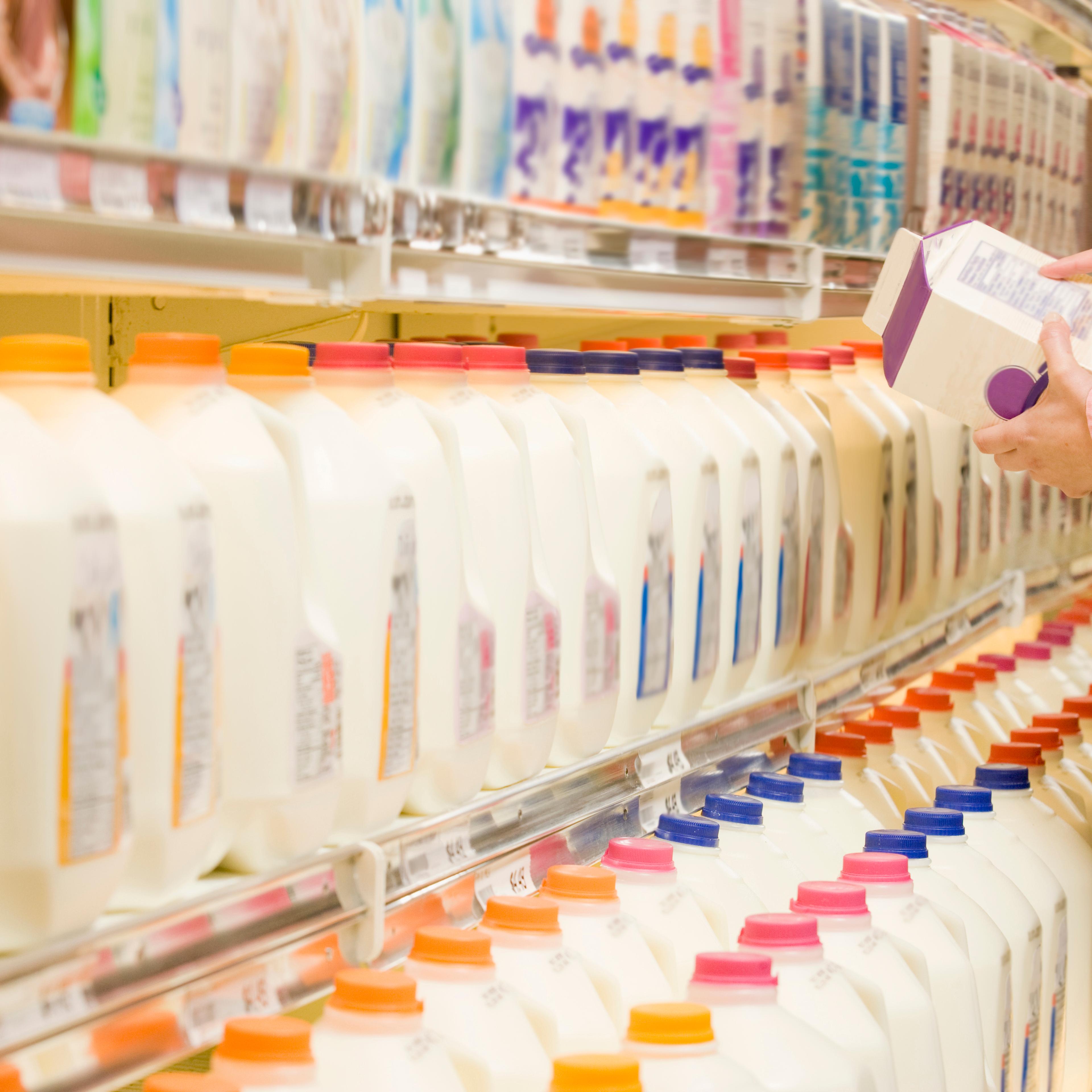 Woman checking ingredients on back of milk carton in supermarket