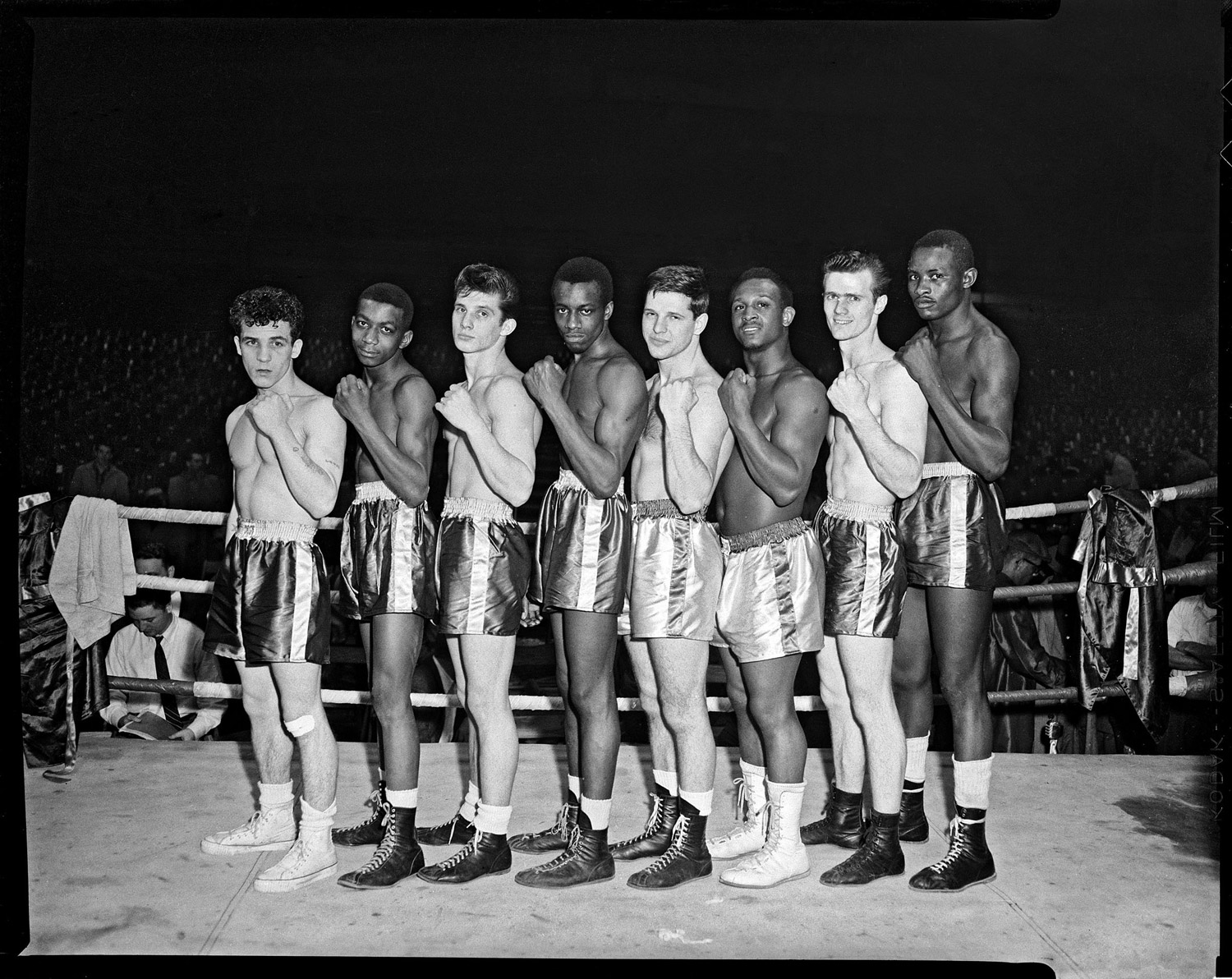 Boxers, possibly Golden Gloves contenders, line up in a boxing ring, 1955.