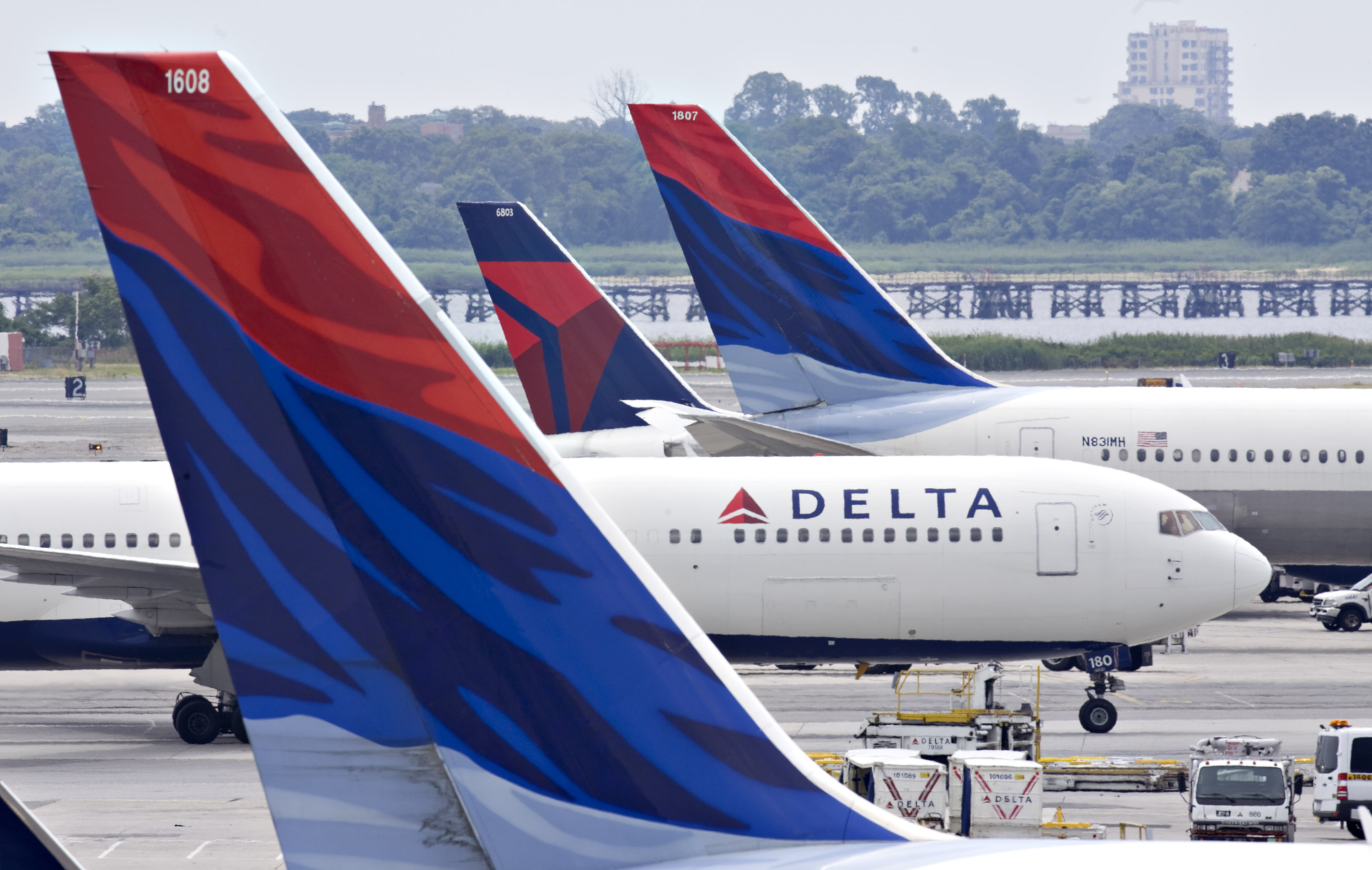 A Delta Air Lines plane taxis toward a gate between other De