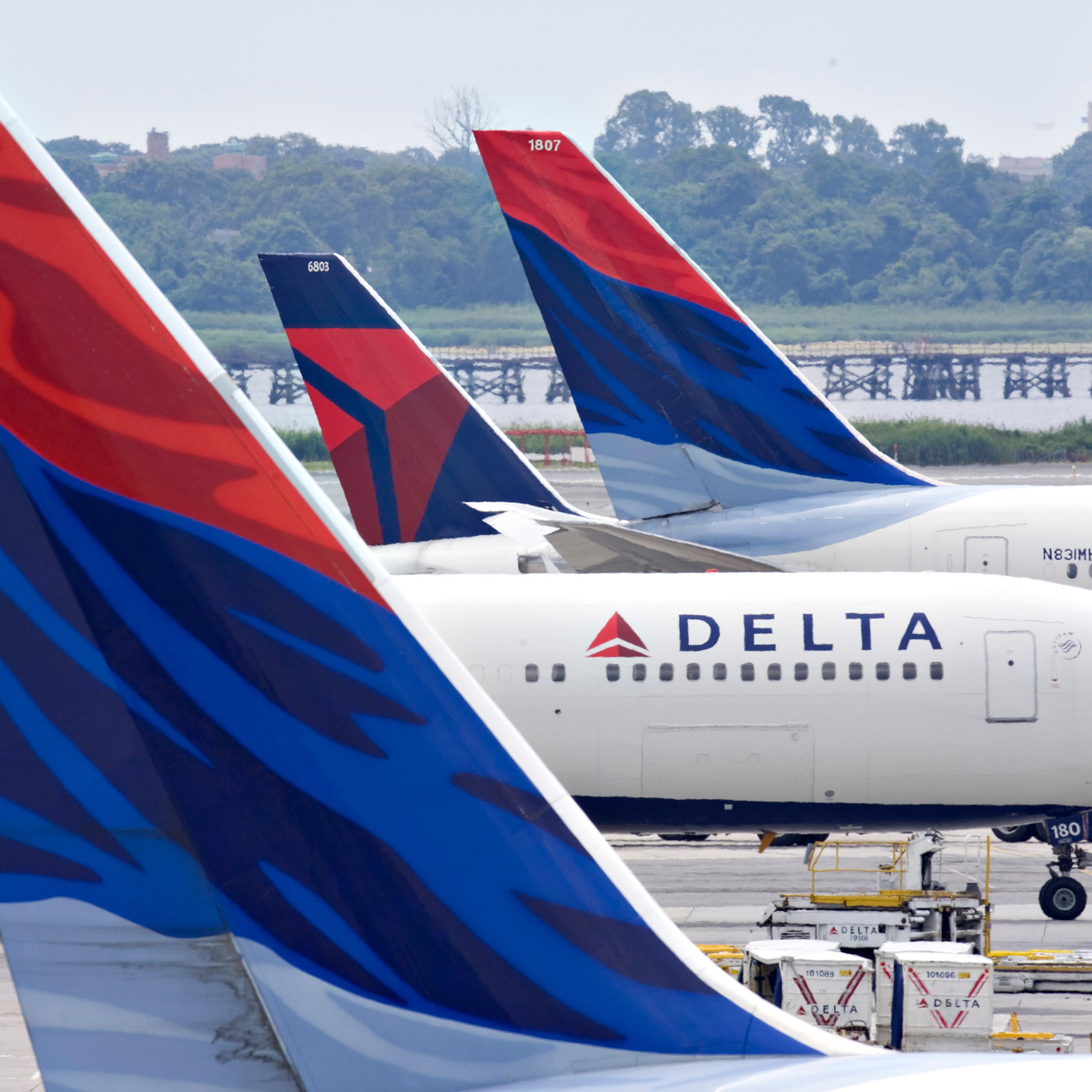 A Delta Air Lines plane taxis toward a gate between other De