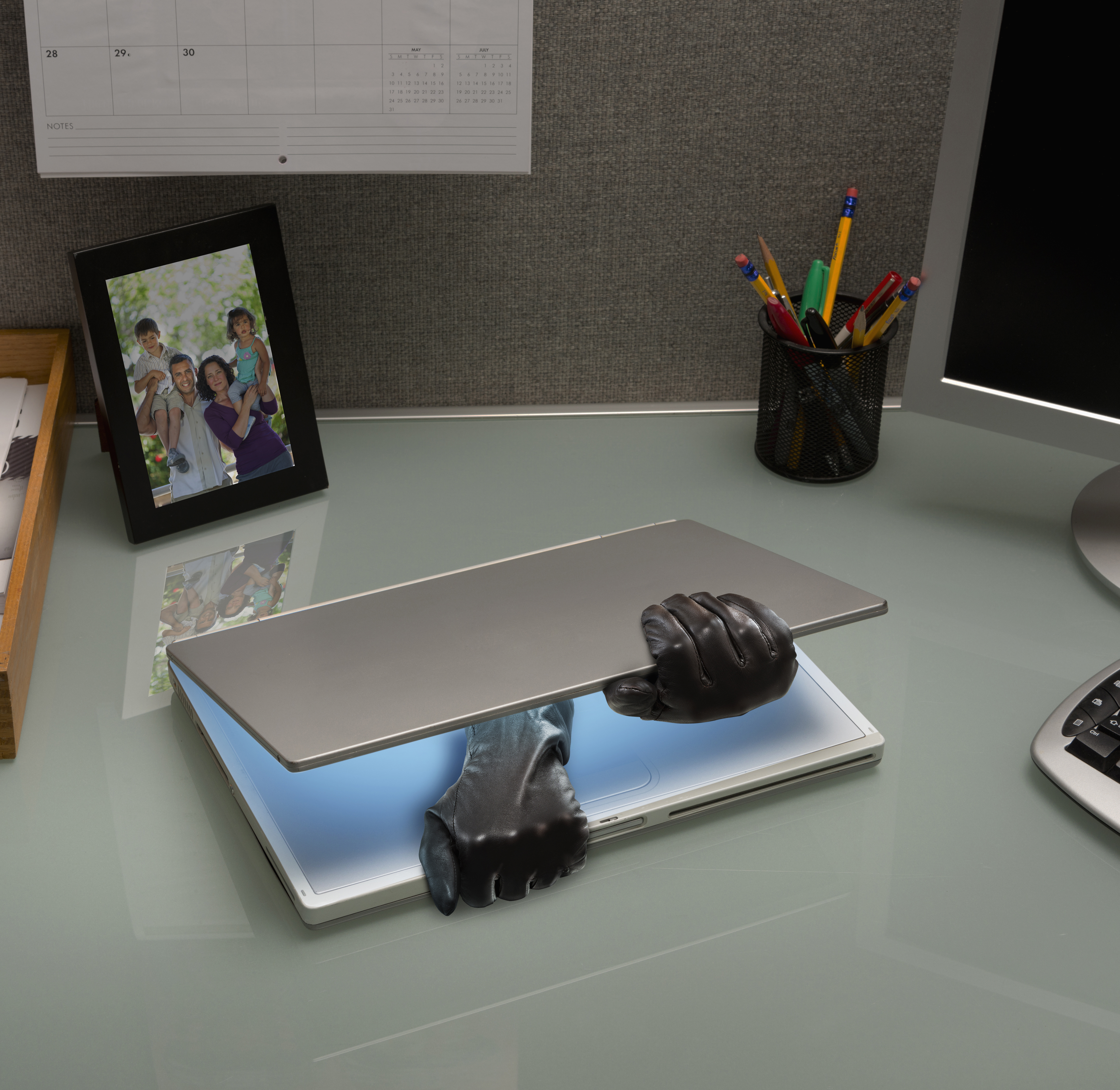 Hacker gloves opening laptop on office desk
