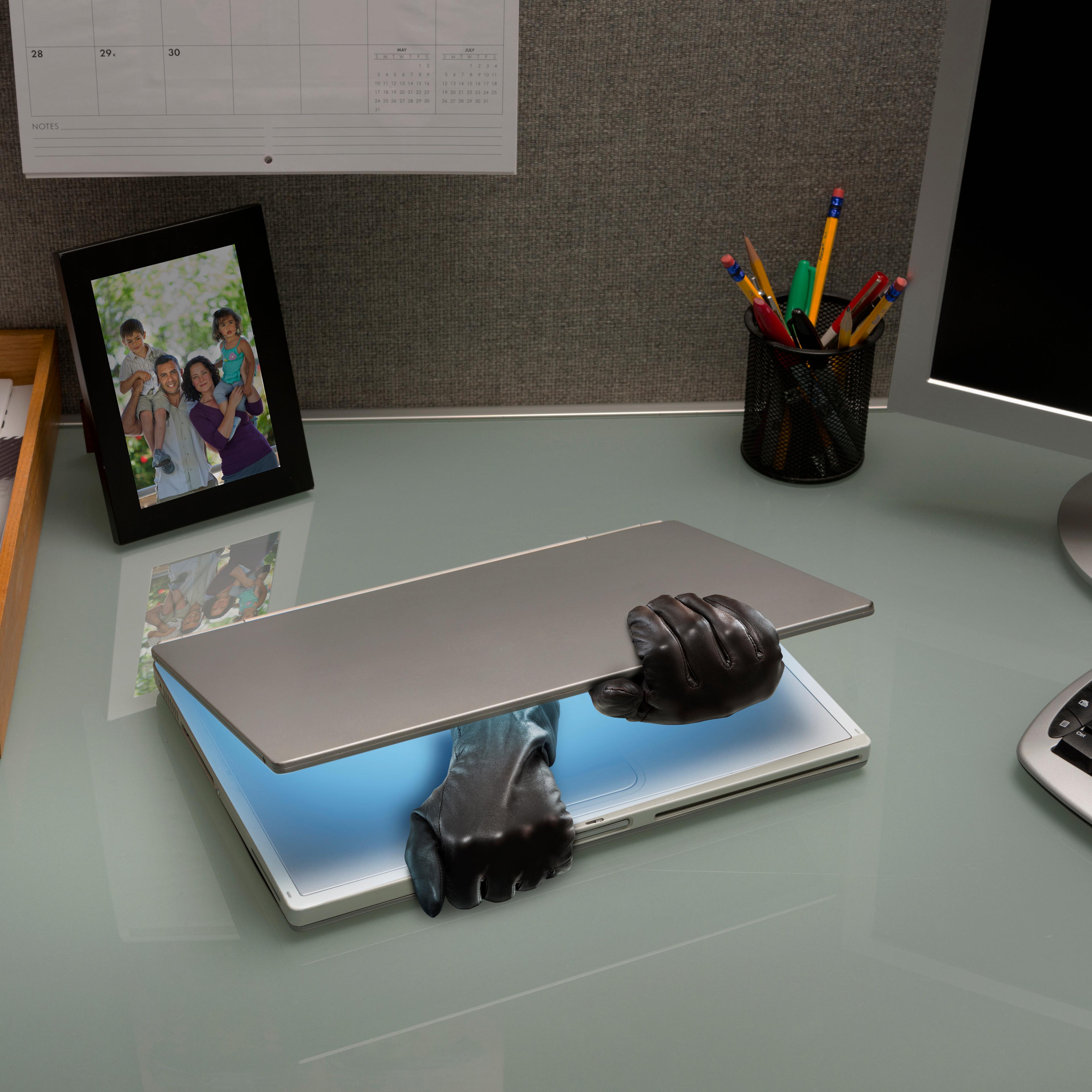 Hacker gloves opening laptop on office desk