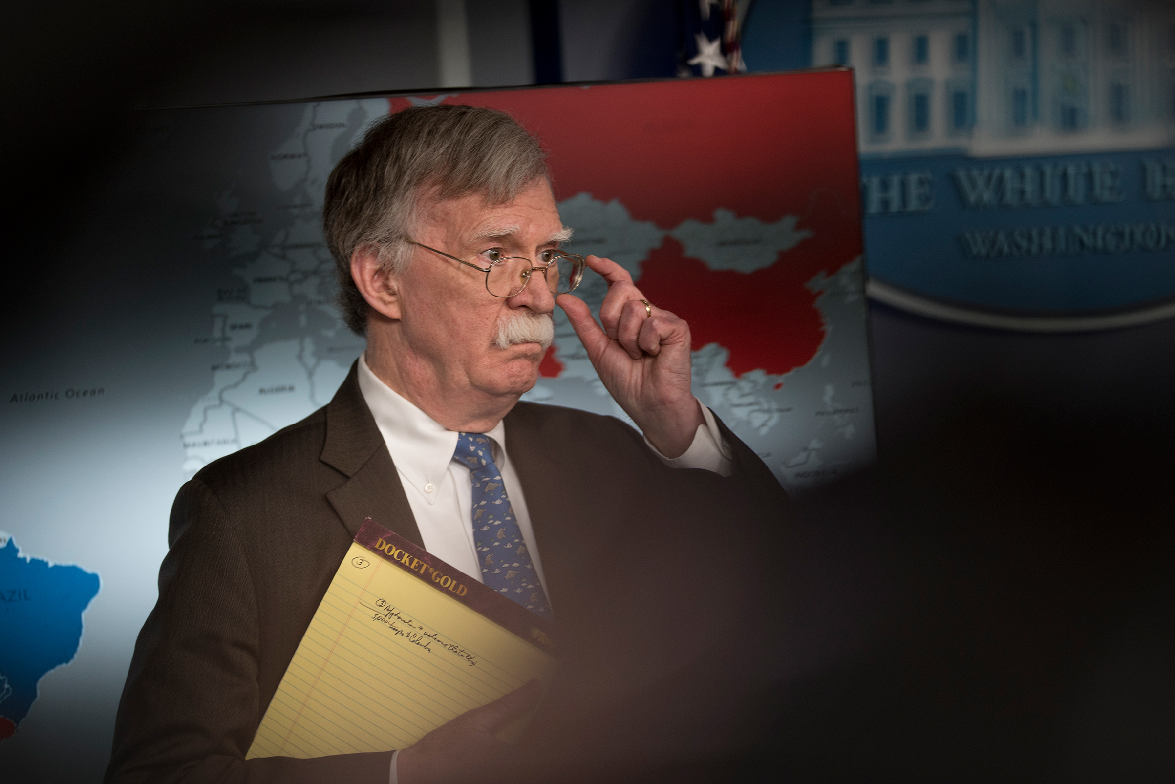 John Bolton holds a yellow legal pad reading "5,000 troops to Colombia."