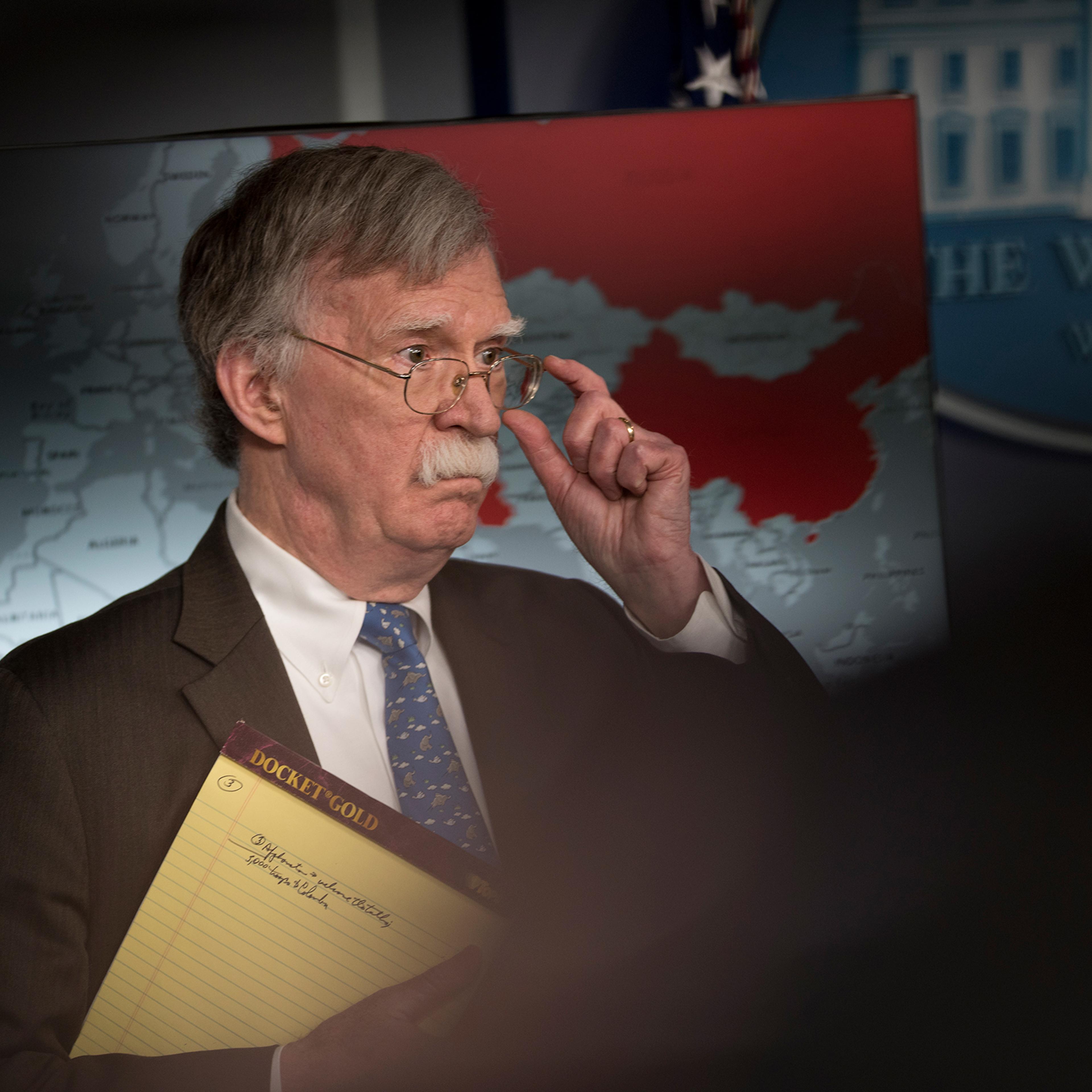 John Bolton holds a yellow legal pad reading "5,000 troops to Colombia."