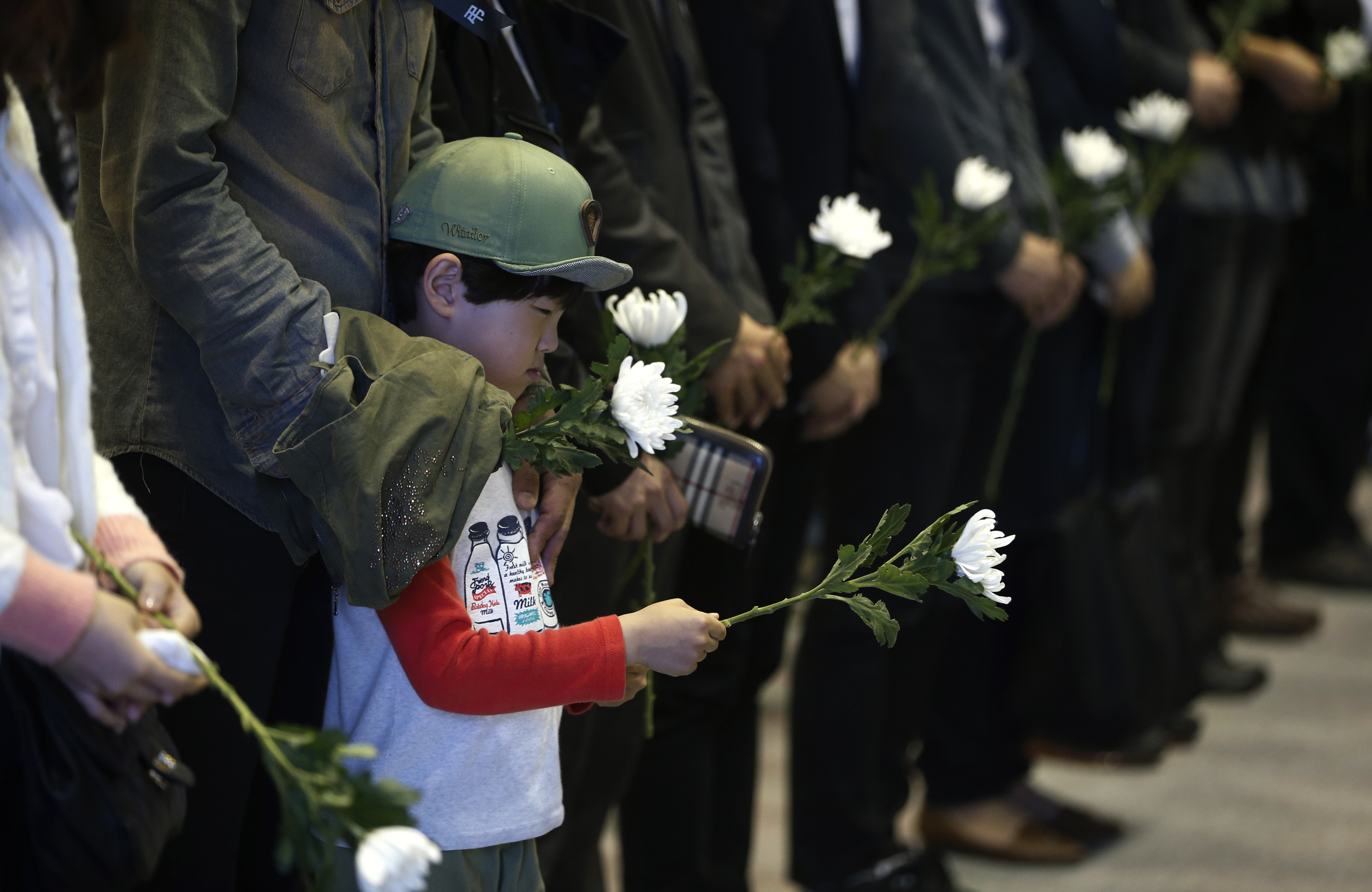 A boy holding a white chrysanthemum pays tribute at a temporary group memorial altar for victims of capsized passenger ship Sewol in Ansan