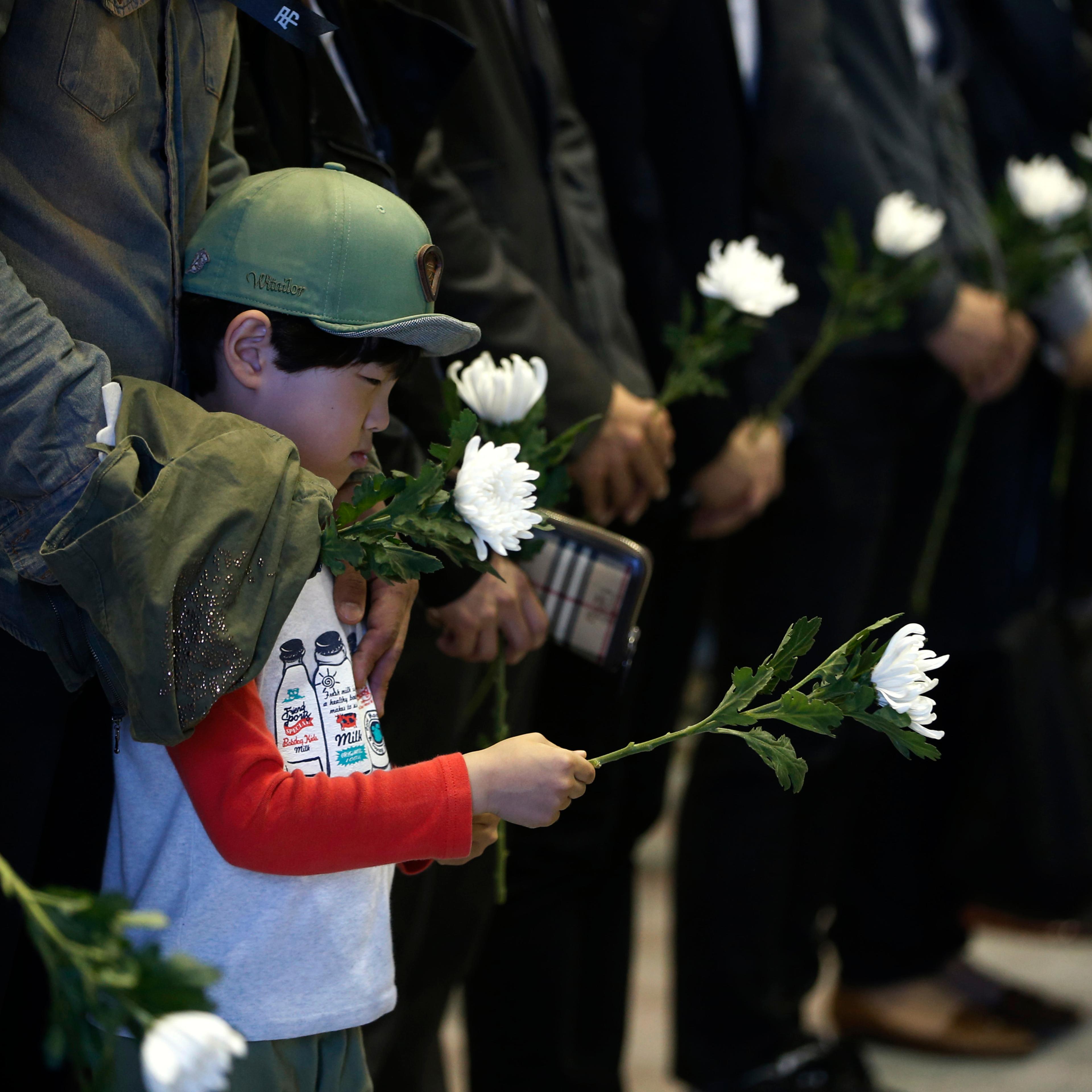 A boy holding a white chrysanthemum pays tribute at a temporary group memorial altar for victims of capsized passenger ship Sewol in Ansan