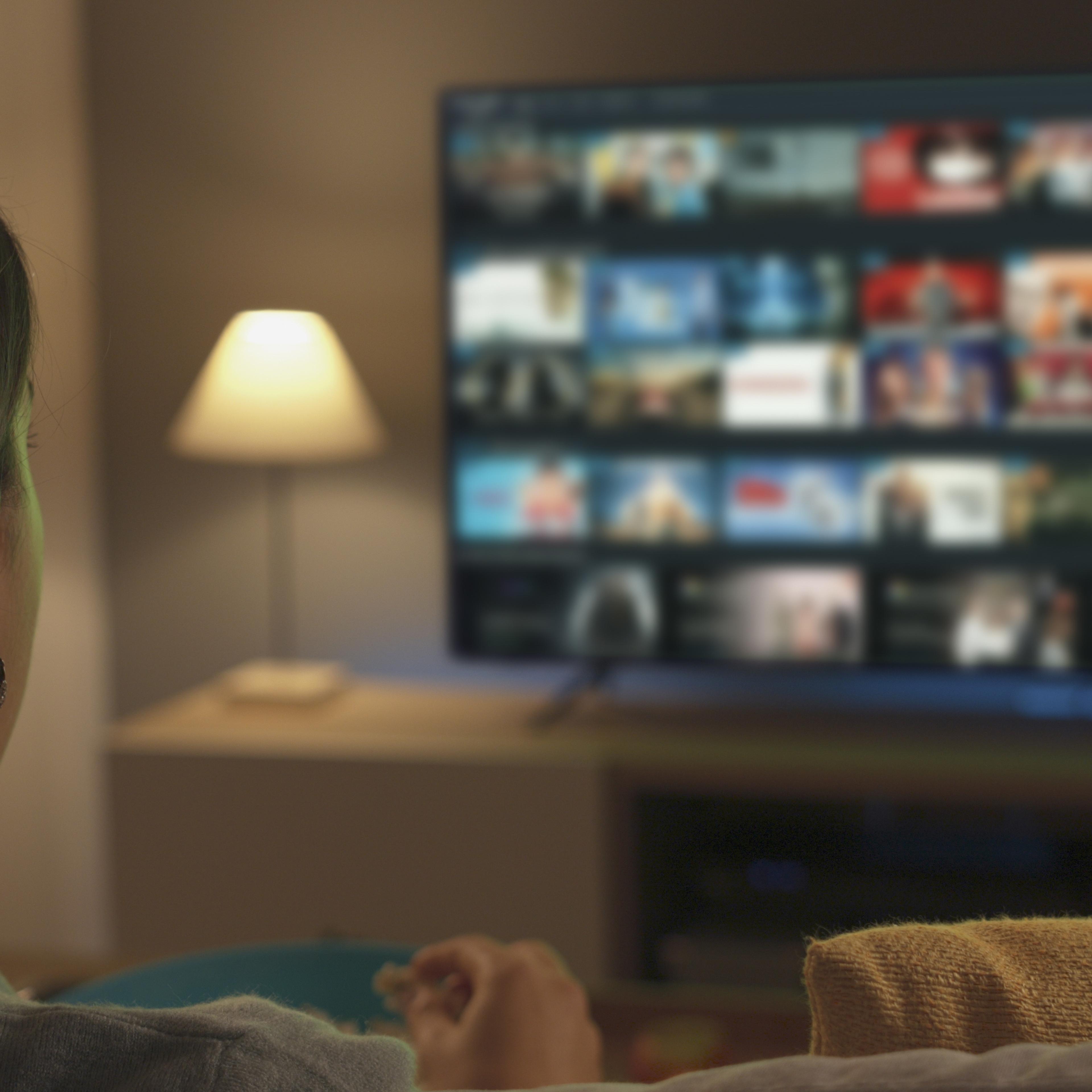 Young woman watching video on demand on her TV
