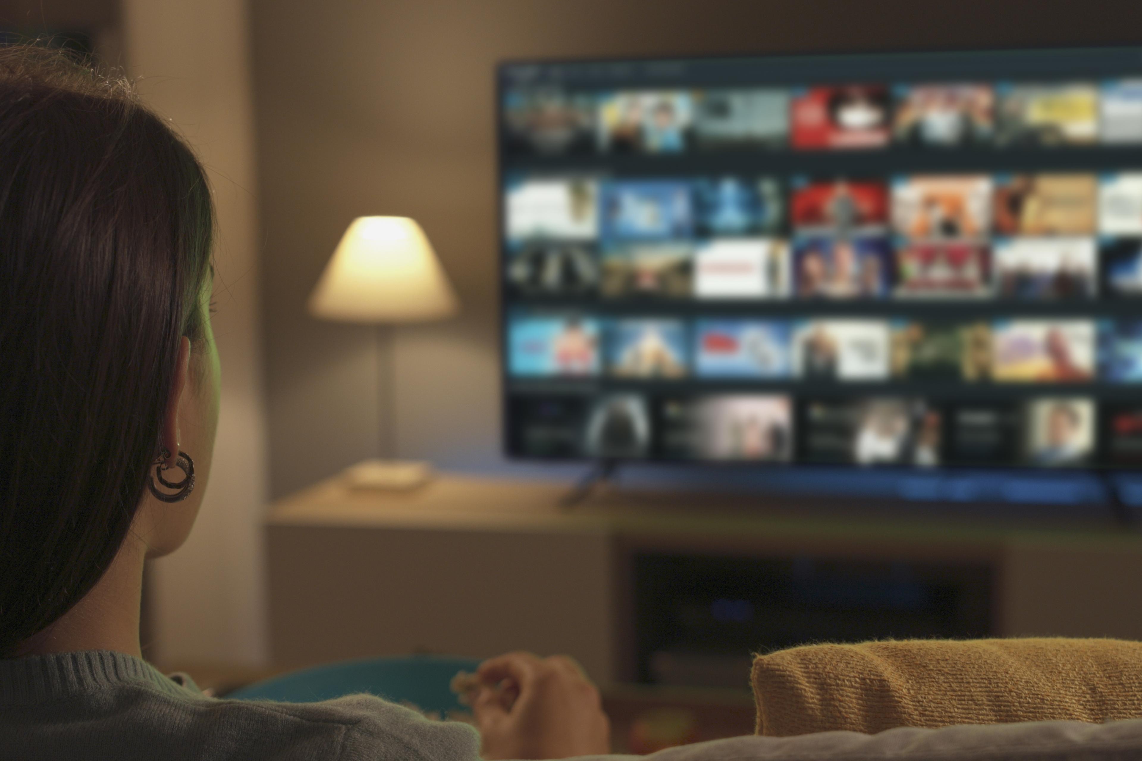 Young woman watching video on demand on her TV