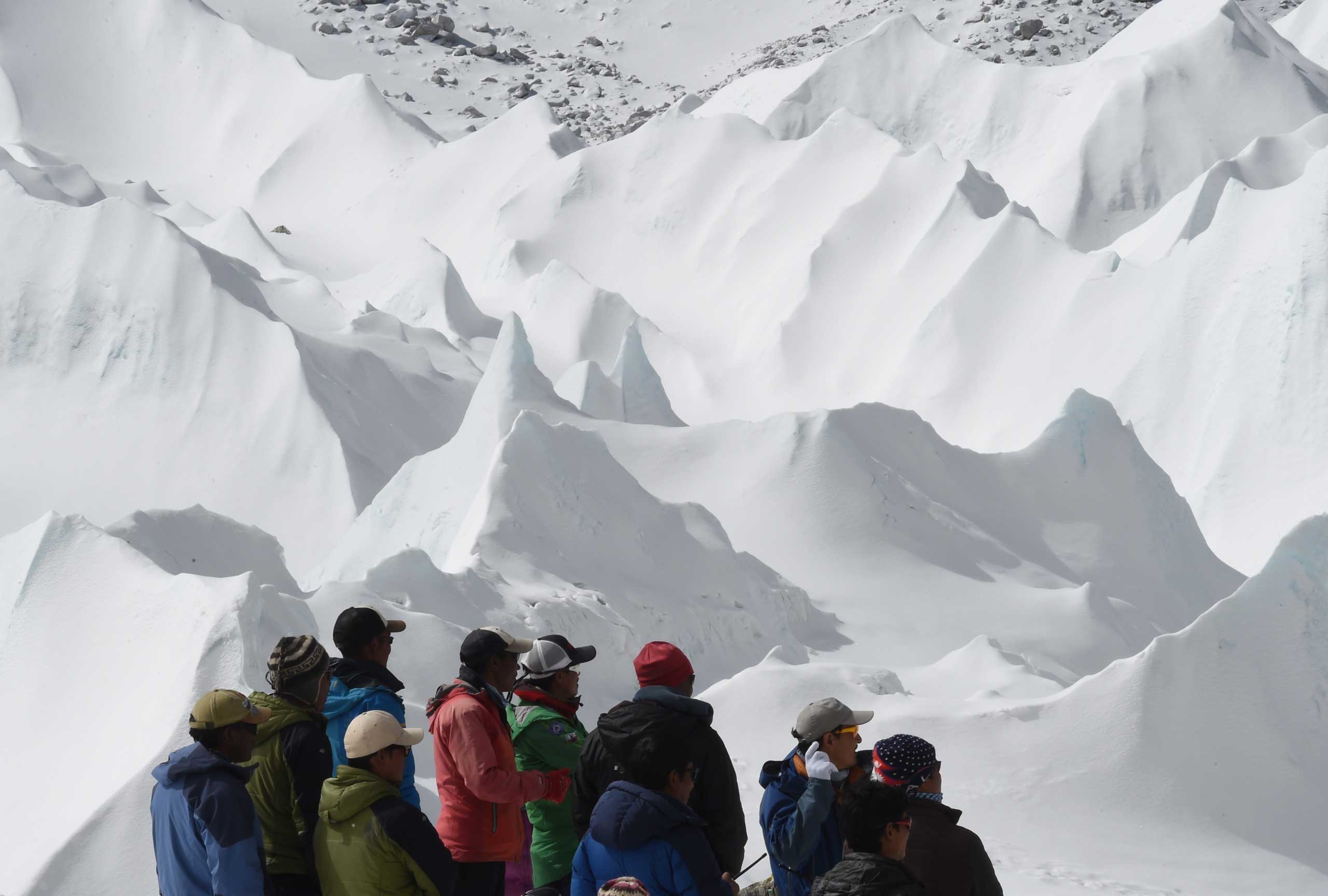 Nepali sherpas and other Nepali members of expeditions watch as an unseen rescue helicopter takes off with the injured from Everest Base Camp on April 26, 2015