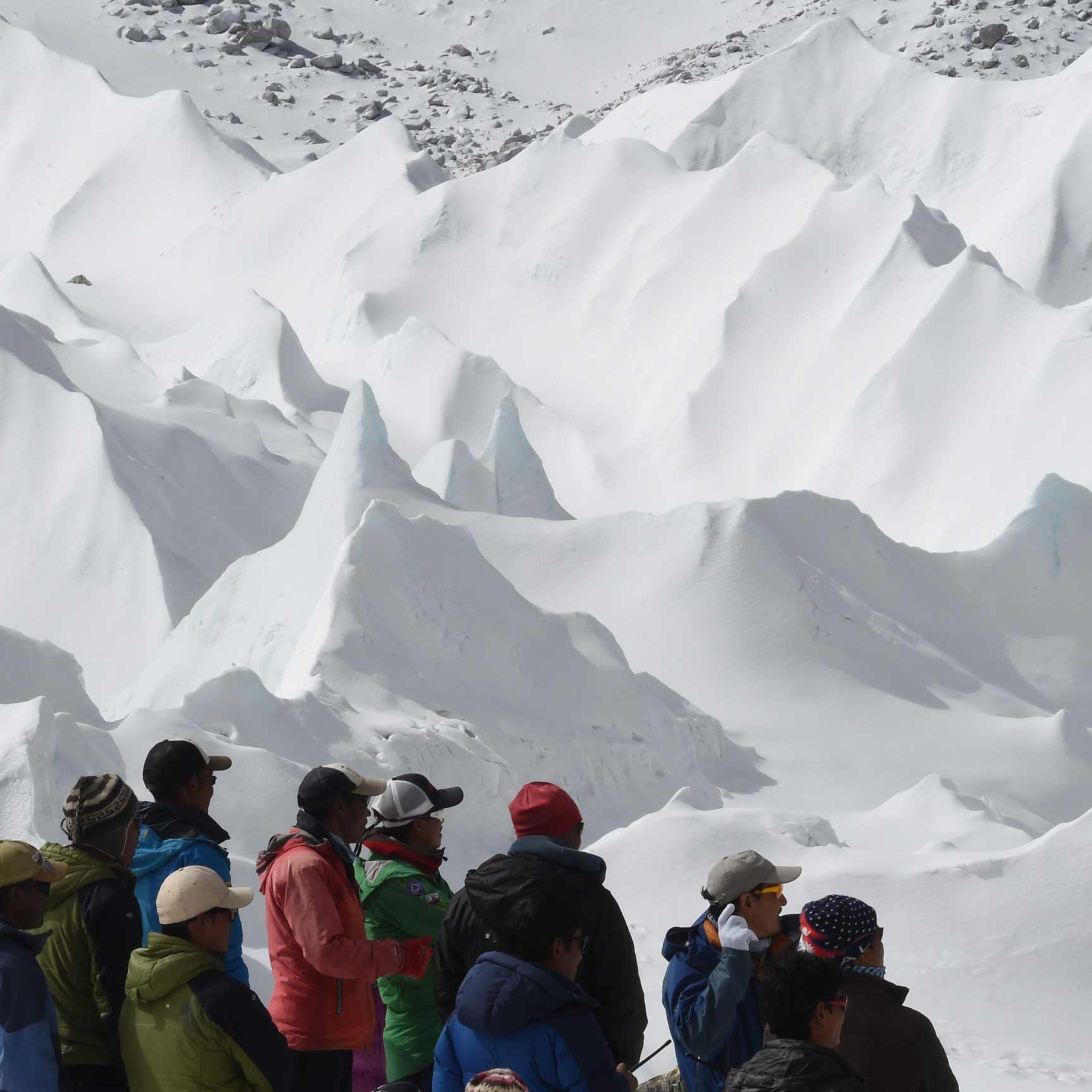 Nepali sherpas and other Nepali members of expeditions watch as an unseen rescue helicopter takes off with the injured from Everest Base Camp on April 26, 2015