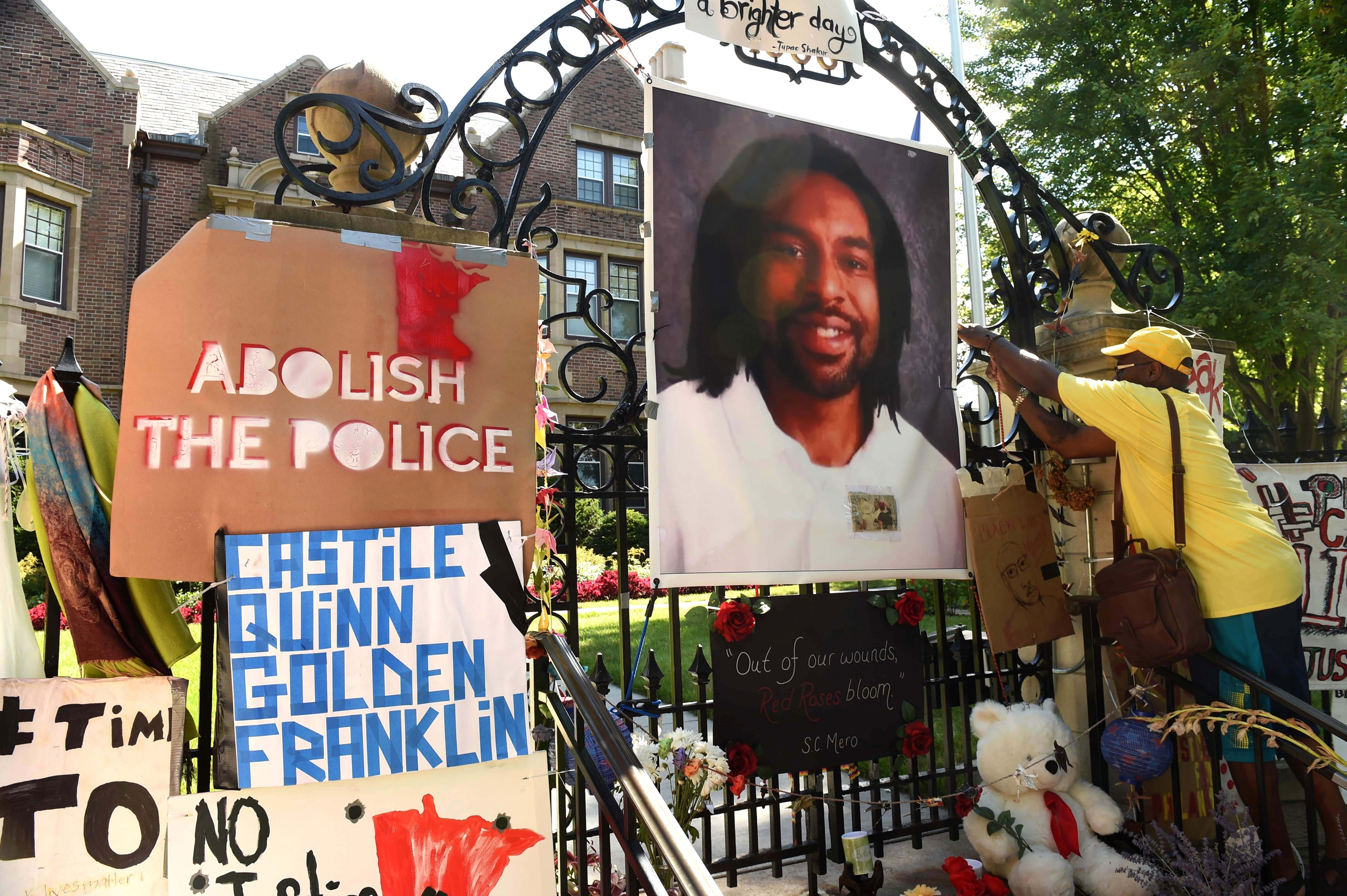 FILE - In this Sunday, July 24, 2016, file photo, King Demetrius Pendleton hangs a sign on the gate of the Governor's Residence in St. Paul, Minn., as protesters demonstrate against the July 6 shooting death of Philando Castile by a St. Anthony police of