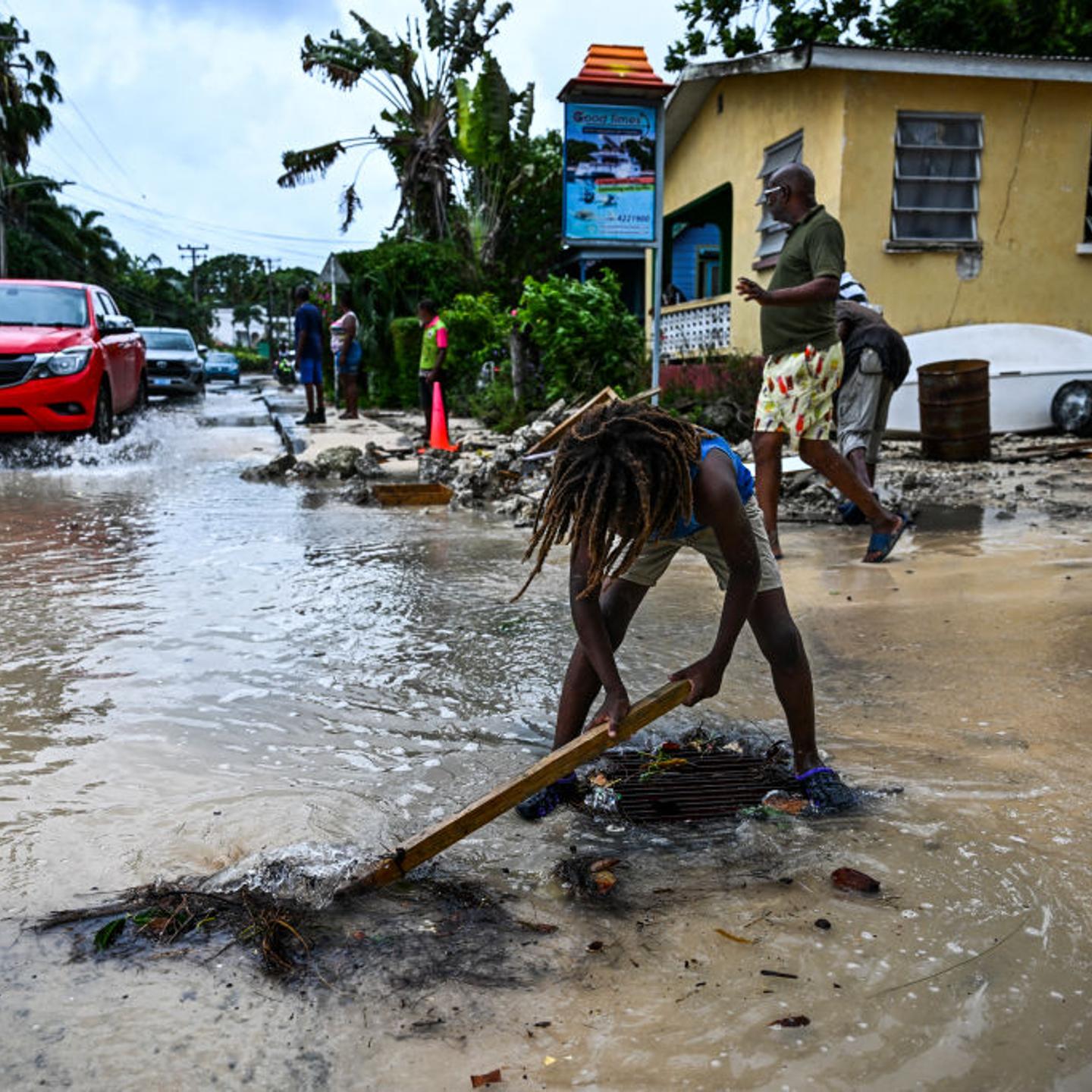 A boy clears rock from the street as it gets flooded after the hurricane Beryl in Barbados.