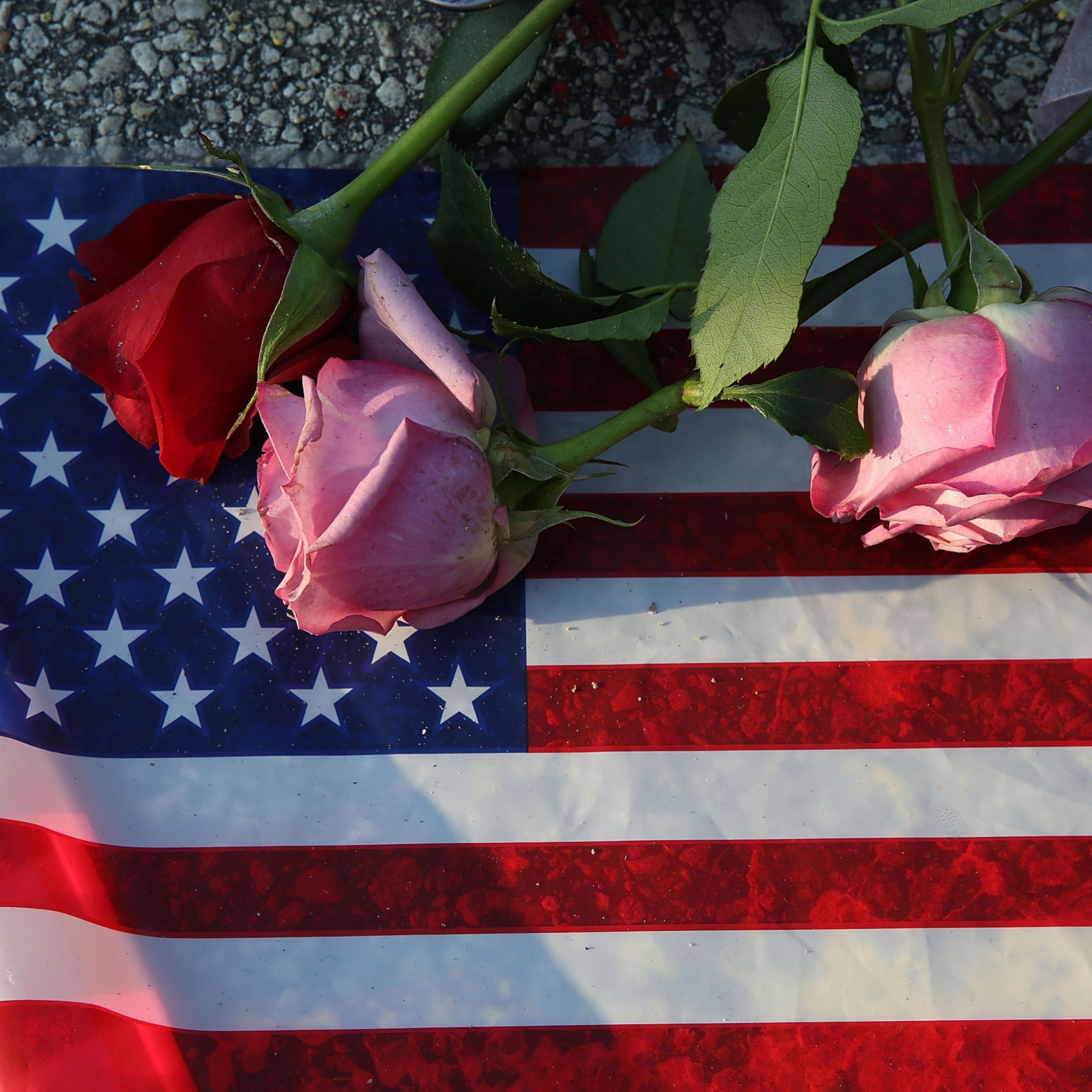 Flowers and an American flag are seen on the ground near the Pulse Nightclub where Omar Mateen allegedly killed at least 50 people in Orlando on June 13, 2016.
