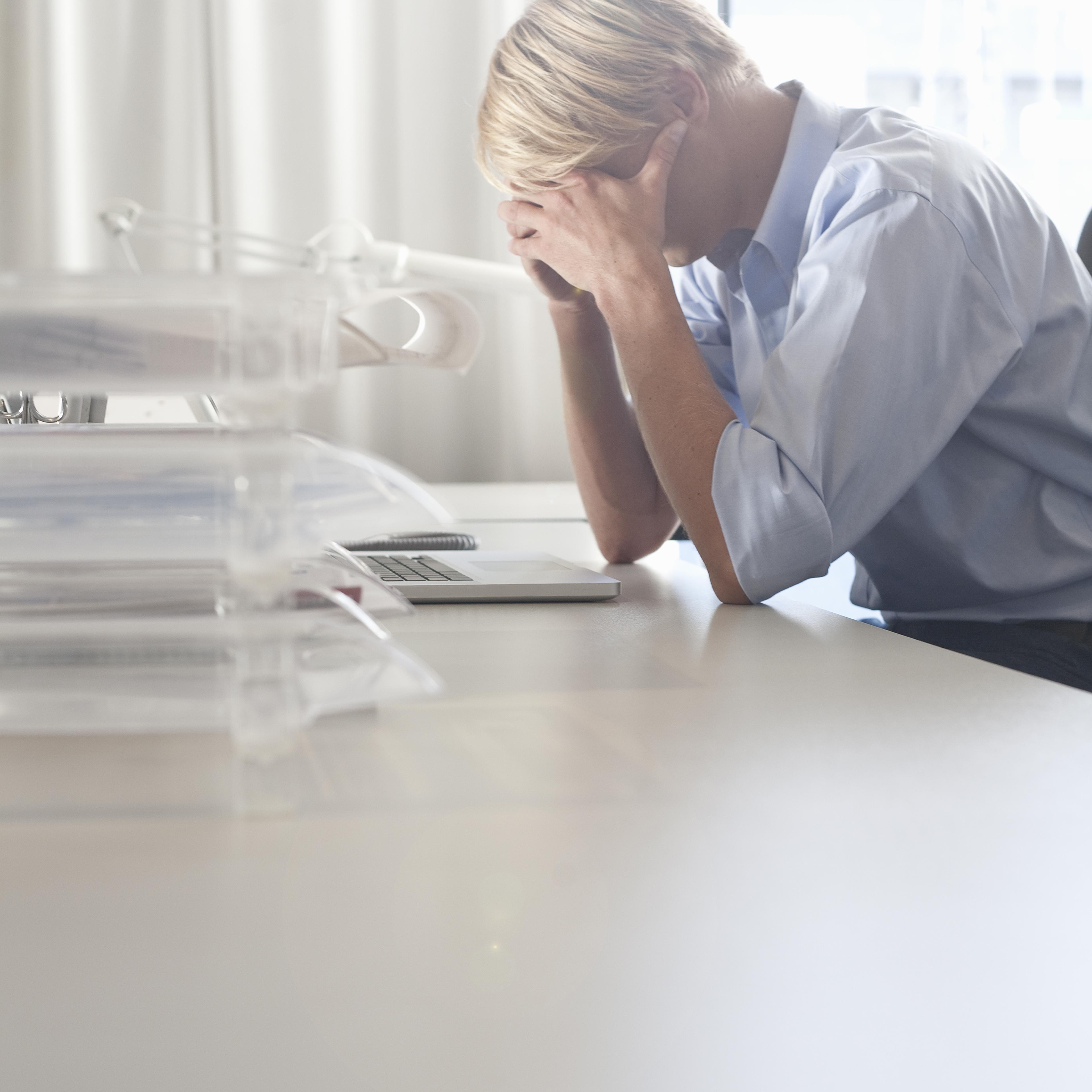 Businessman holding his head at desk
